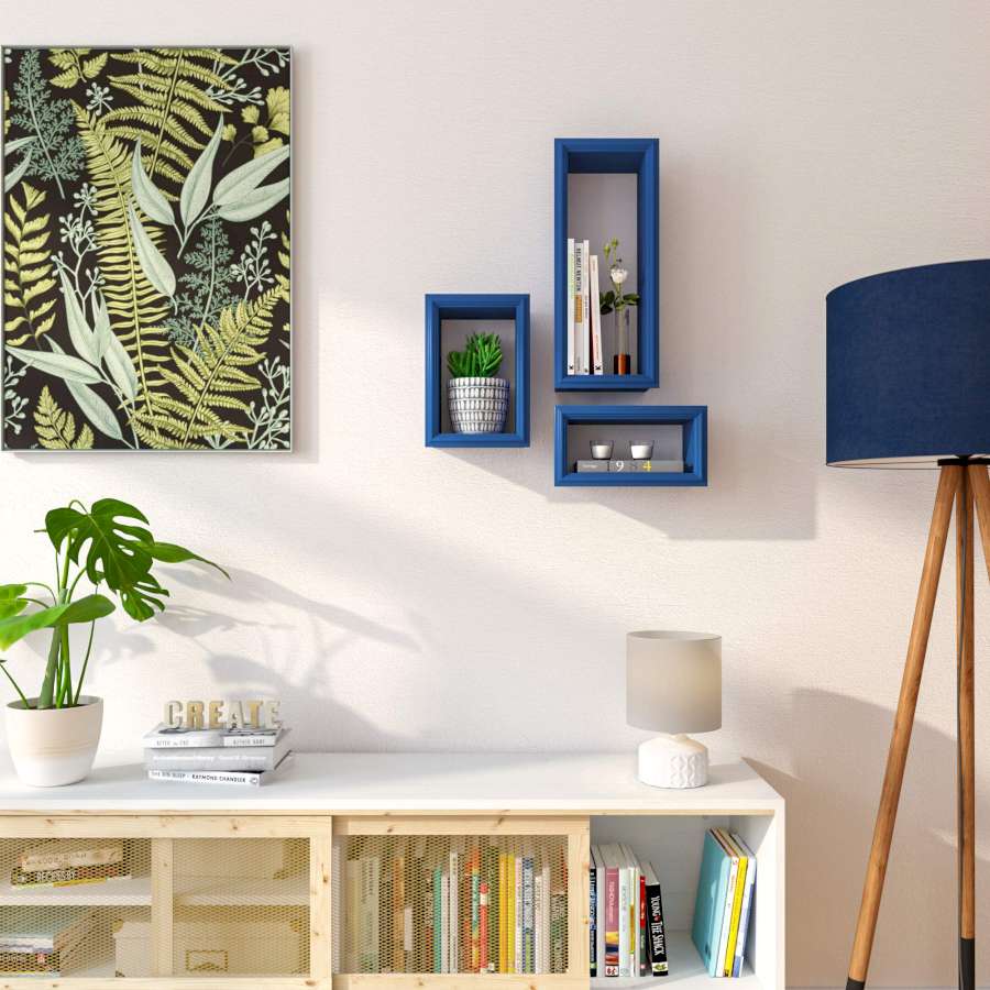 Blaue Rahmenregale an weißer Wand neben grünem Bild, Steh- und Tischlampe und weißem Standregal