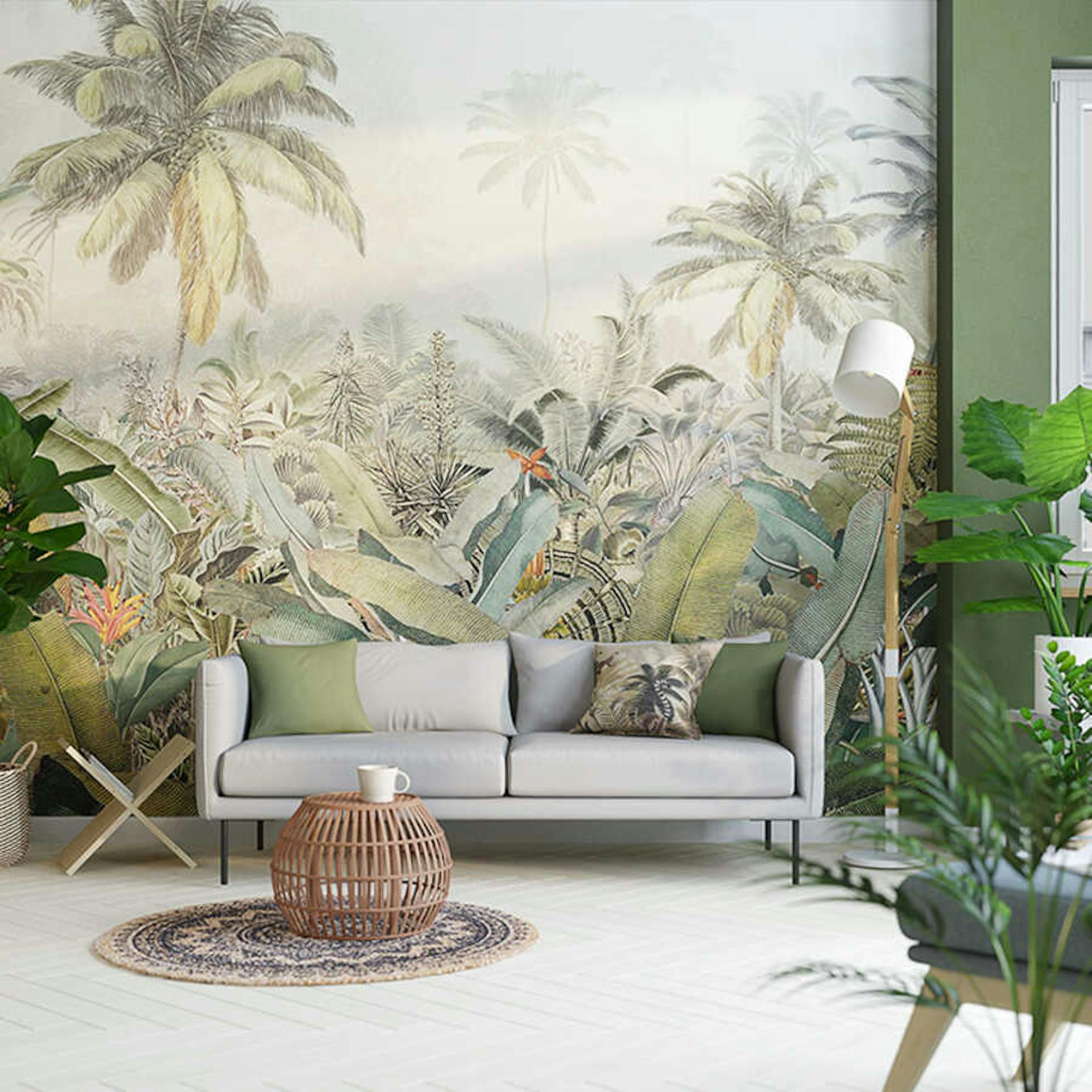 Ein helles Sofa , wo neben ihm ein Magazinhalter platziert ist, steht zentriert vor einer Wand mit großer Dschungelmotiv-Tapete.