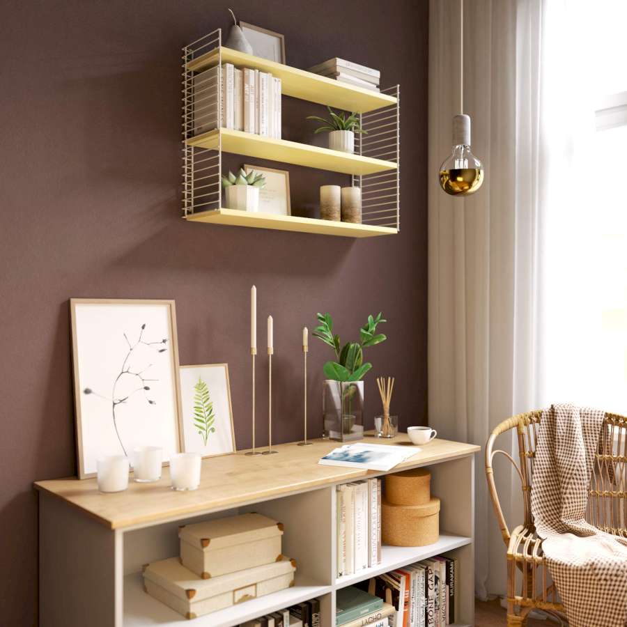Regale, Stuhl und Dekoration vor einer dunkelbraun gestrichenen Wand