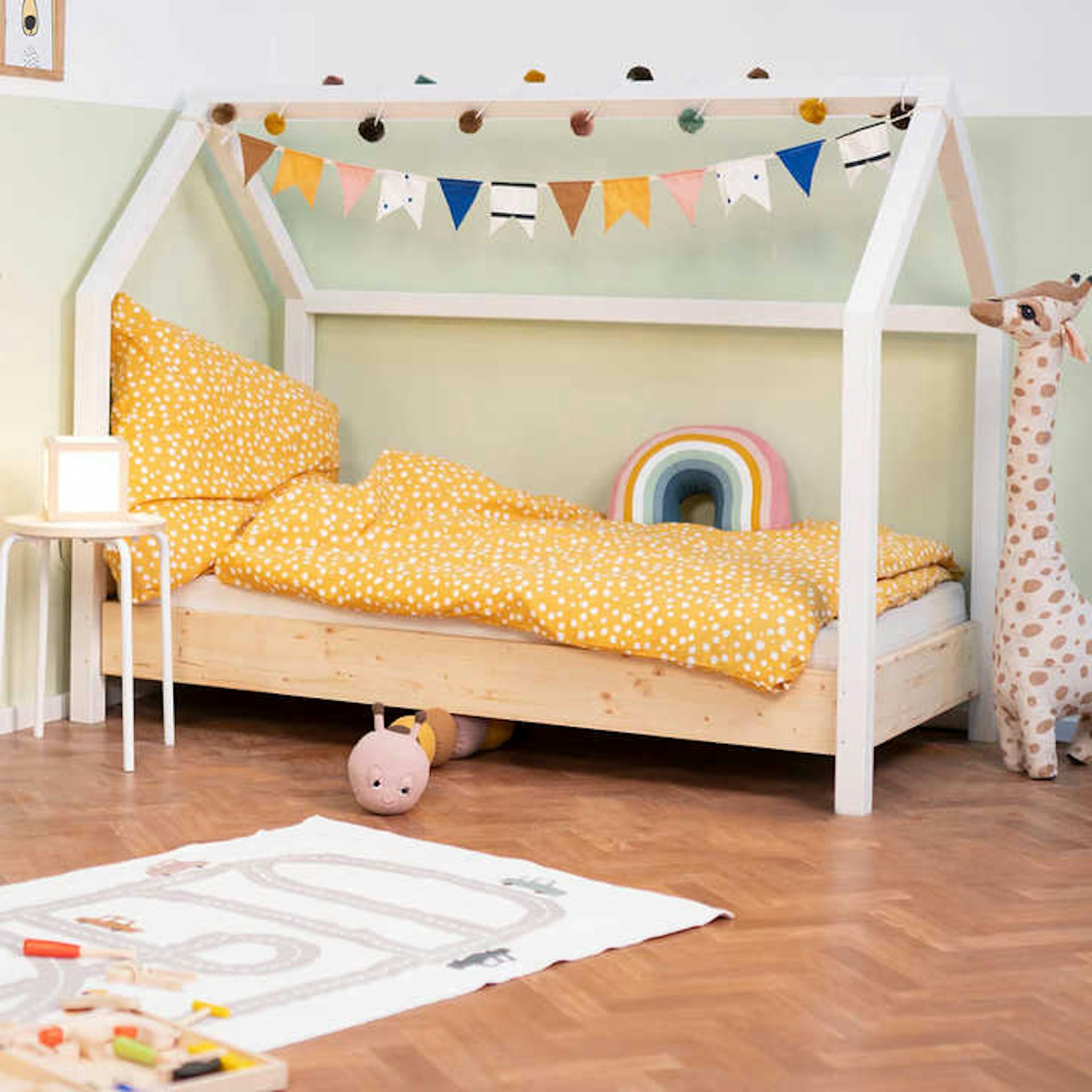 Kinderbett aus Massivholz mit gelber Bettwäsche und bunter Dekoration