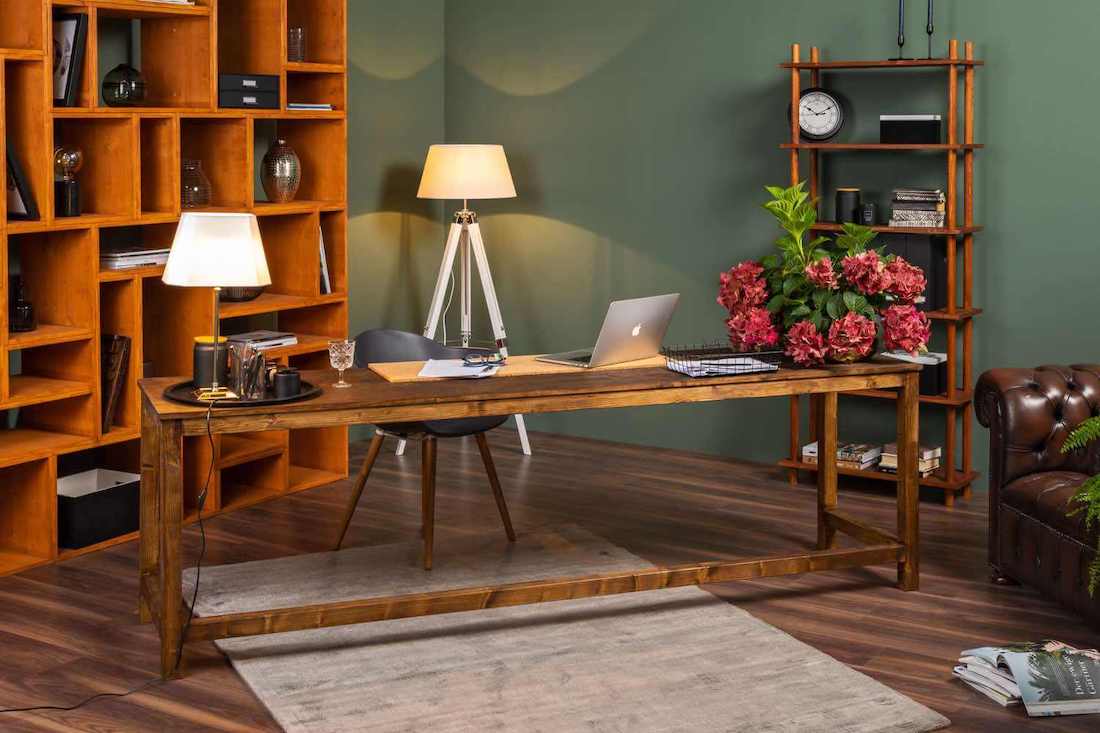 In einem Arbeitszimmer mit grünen Wänden steht Schreibtisch Egon mit einem Stuhl vor zwei Regalen und einer Lampe.