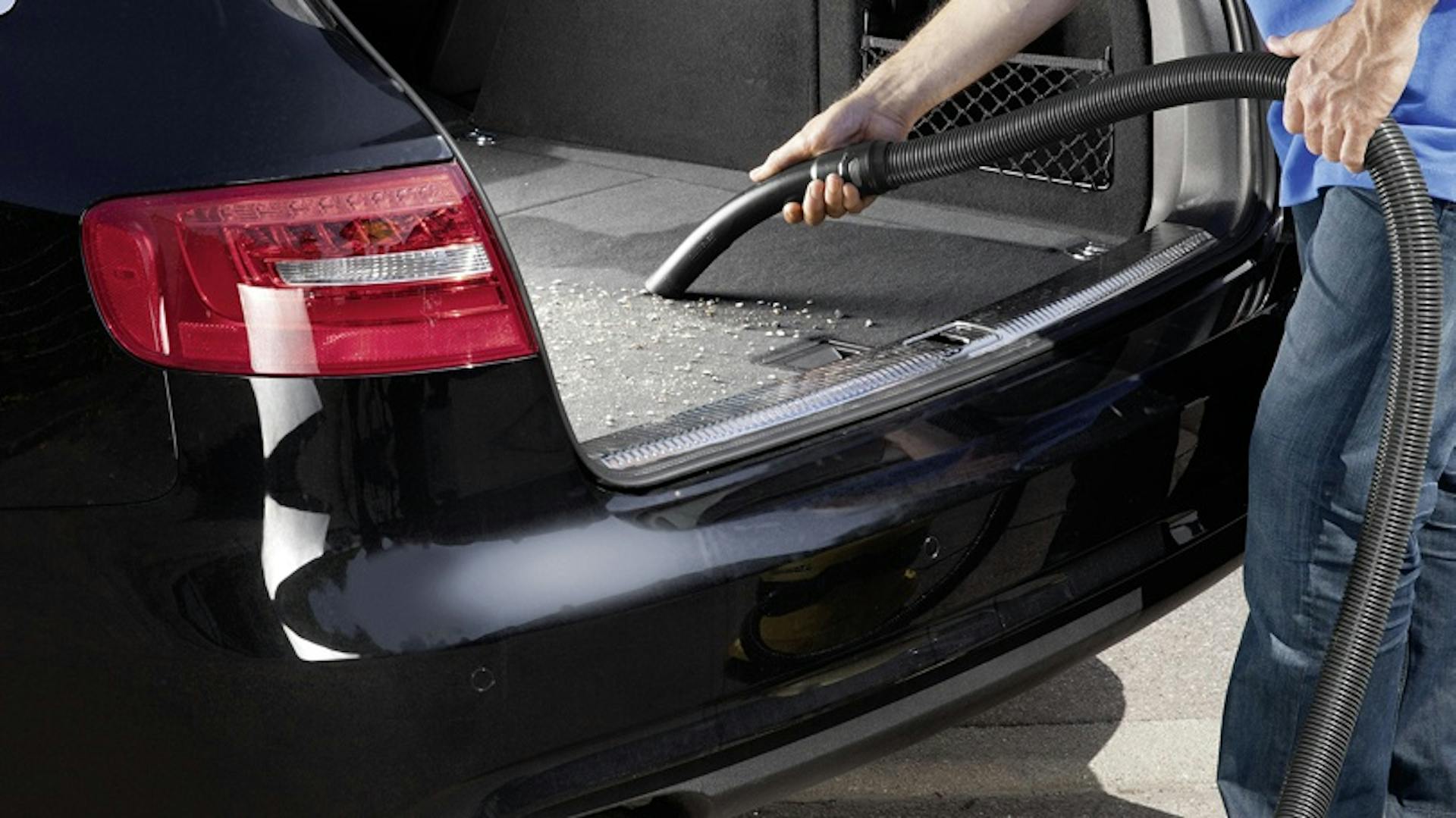 Mann saugt Kofferraum von Auto aus.