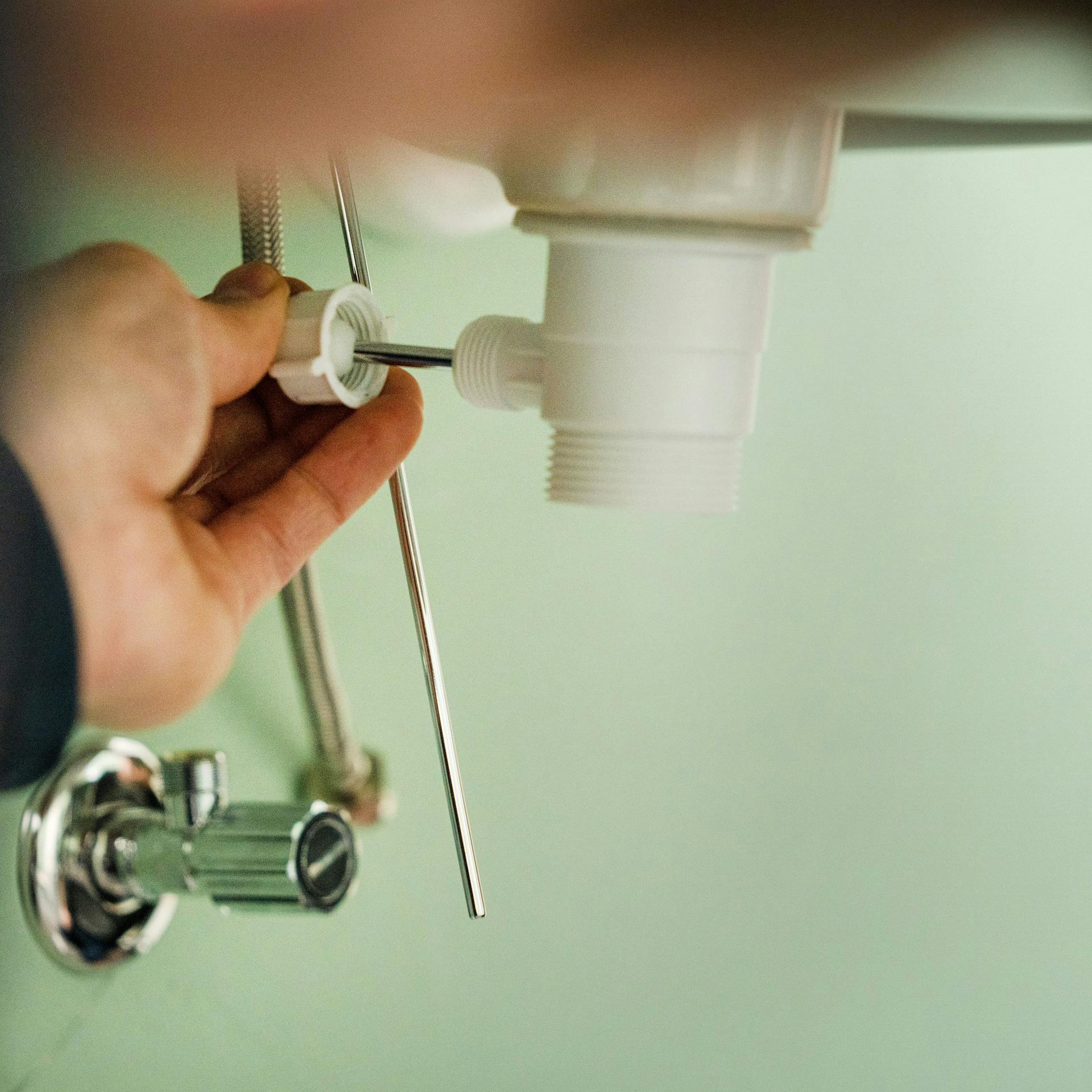 Ein Handwerker bringt das Ablaufsieb unter dem Waschbecken an.