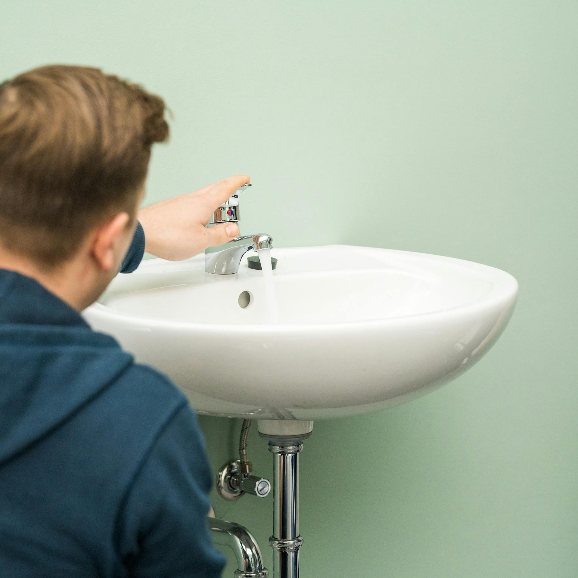 Handwerker lässt die Leitungen leer laufen.