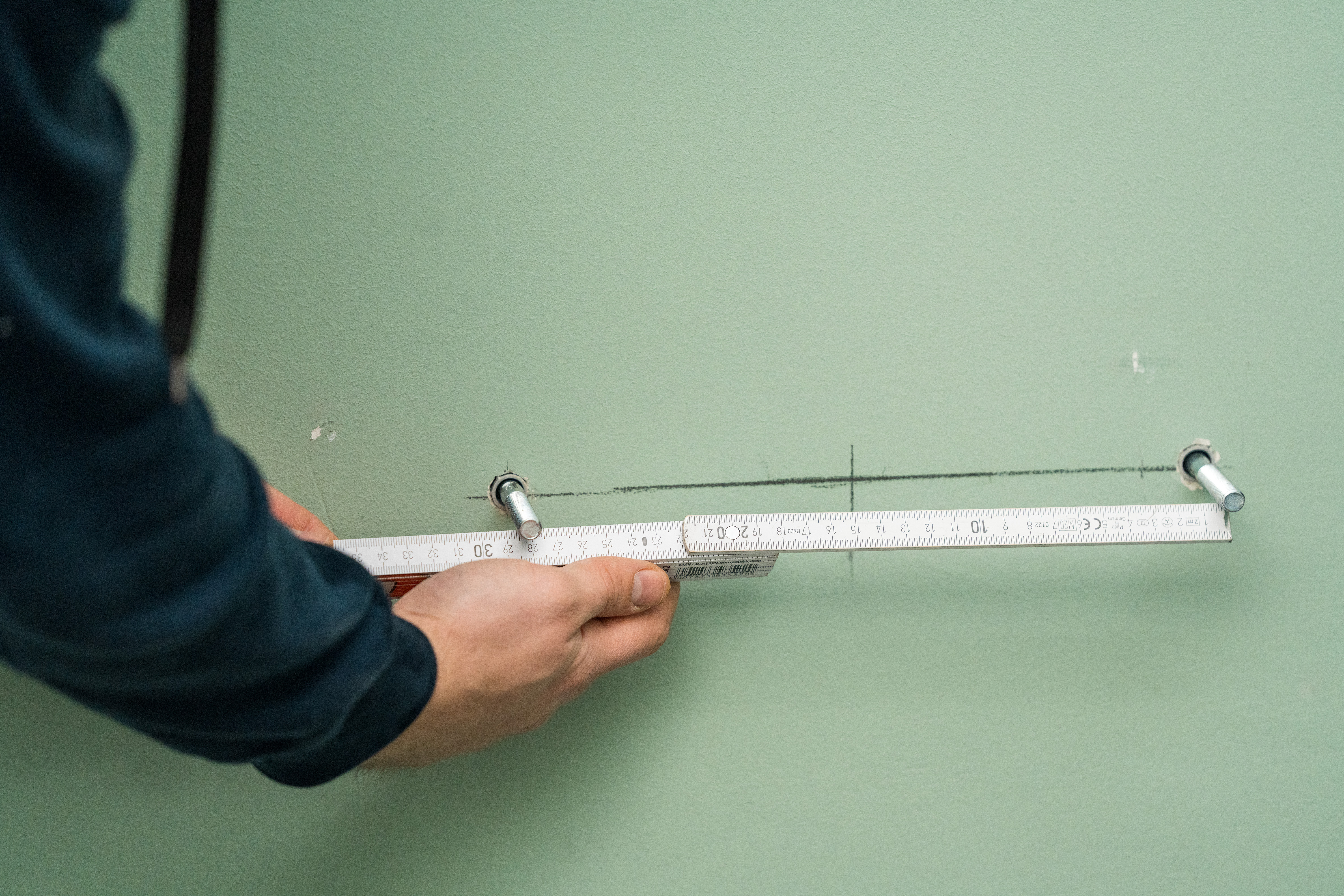 Un appassionato del fai da te utilizza la livella a bolla per praticare in seguito fori per viti a doppia filettatura con la punta accanto 