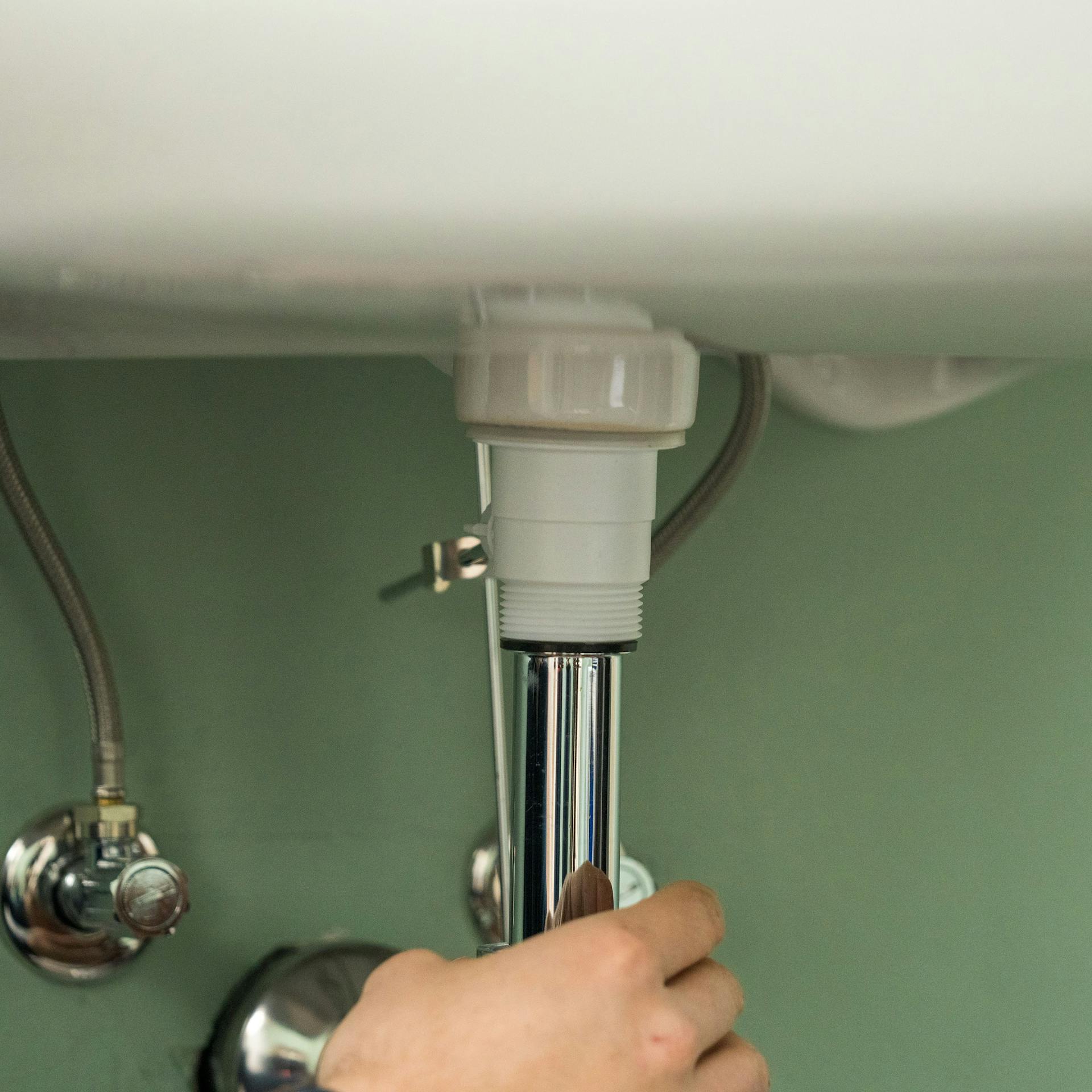 Hand montiert Siphon an Waschbecken.