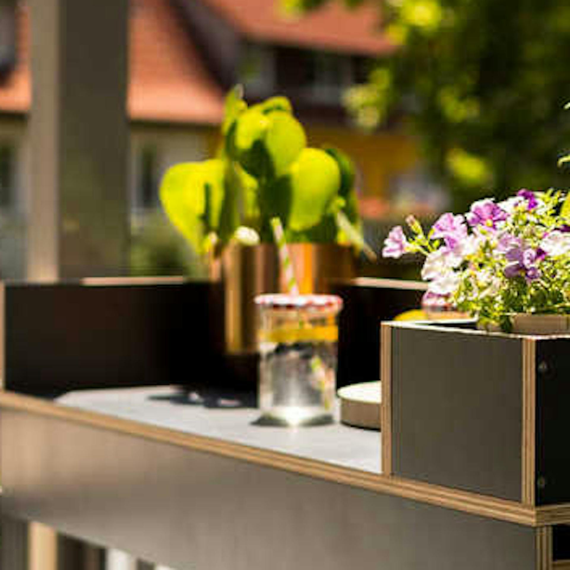 Eine Balkonbar mit Pflanzen und Getränken im Sonnenlicht