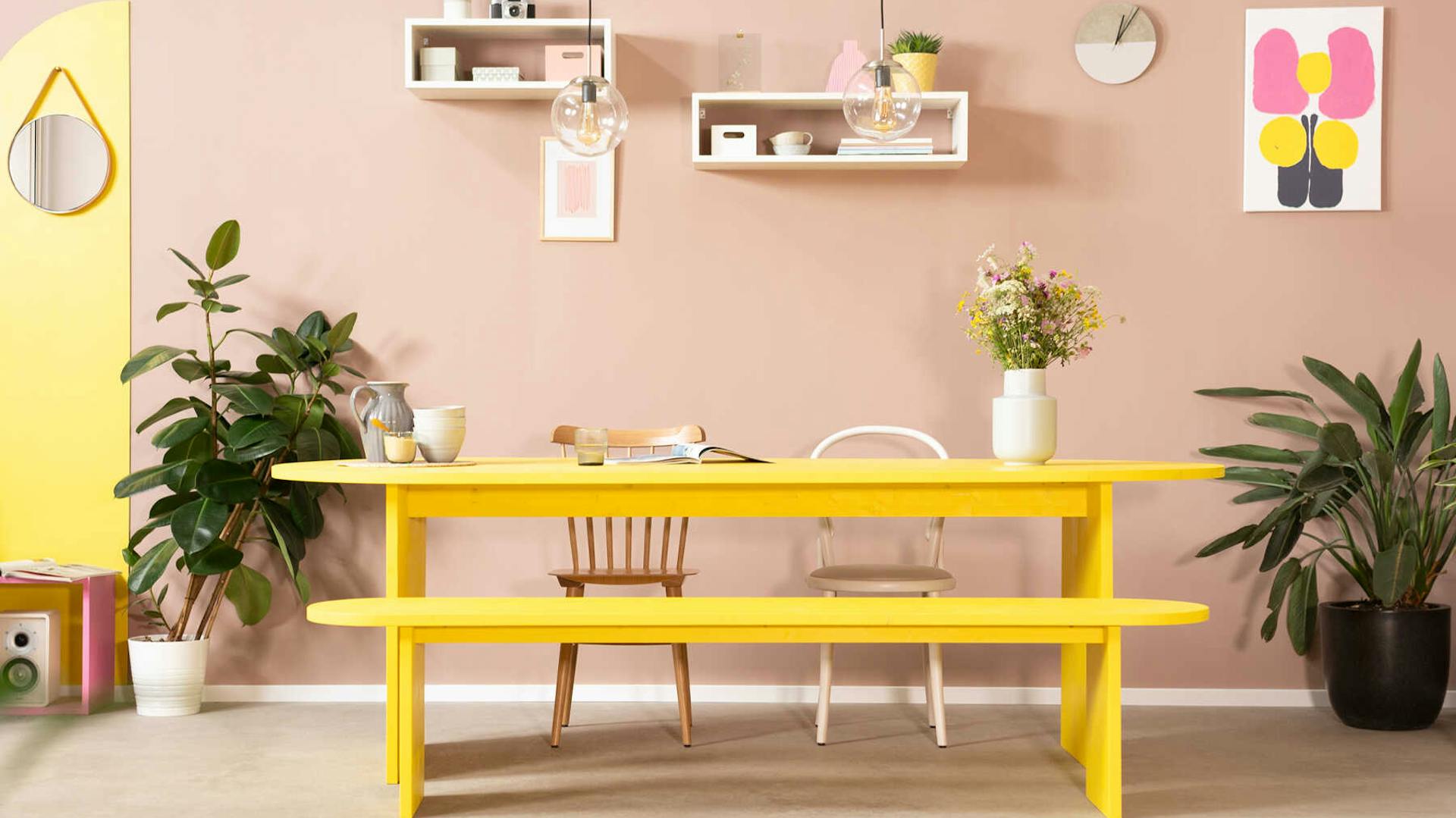 Frontansicht der aus Vollholz bestehenden Bank Clemens mit abgerundeten Ecken in weiß mit entsprechenden Tisch Clemens im Hintergrund.