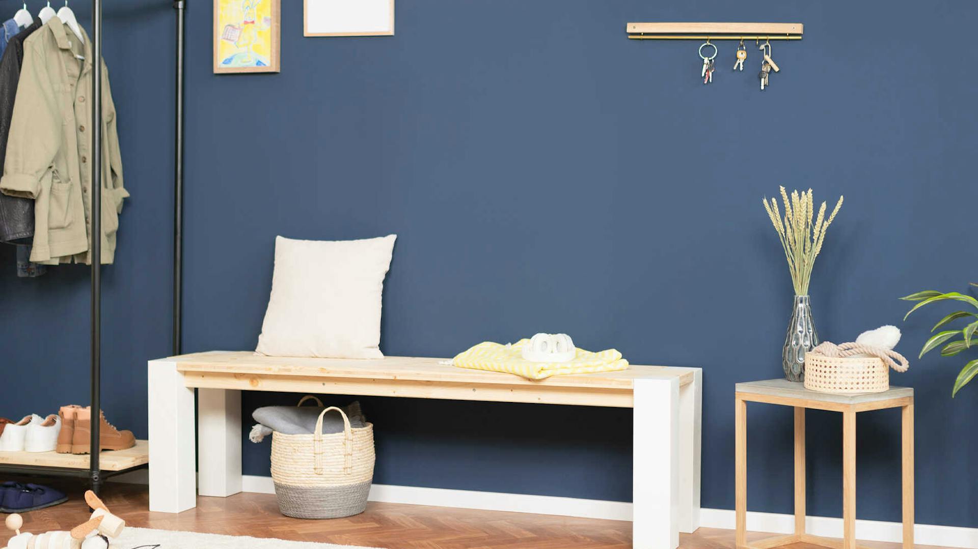 Bank Maren vor einer blauen Wand.