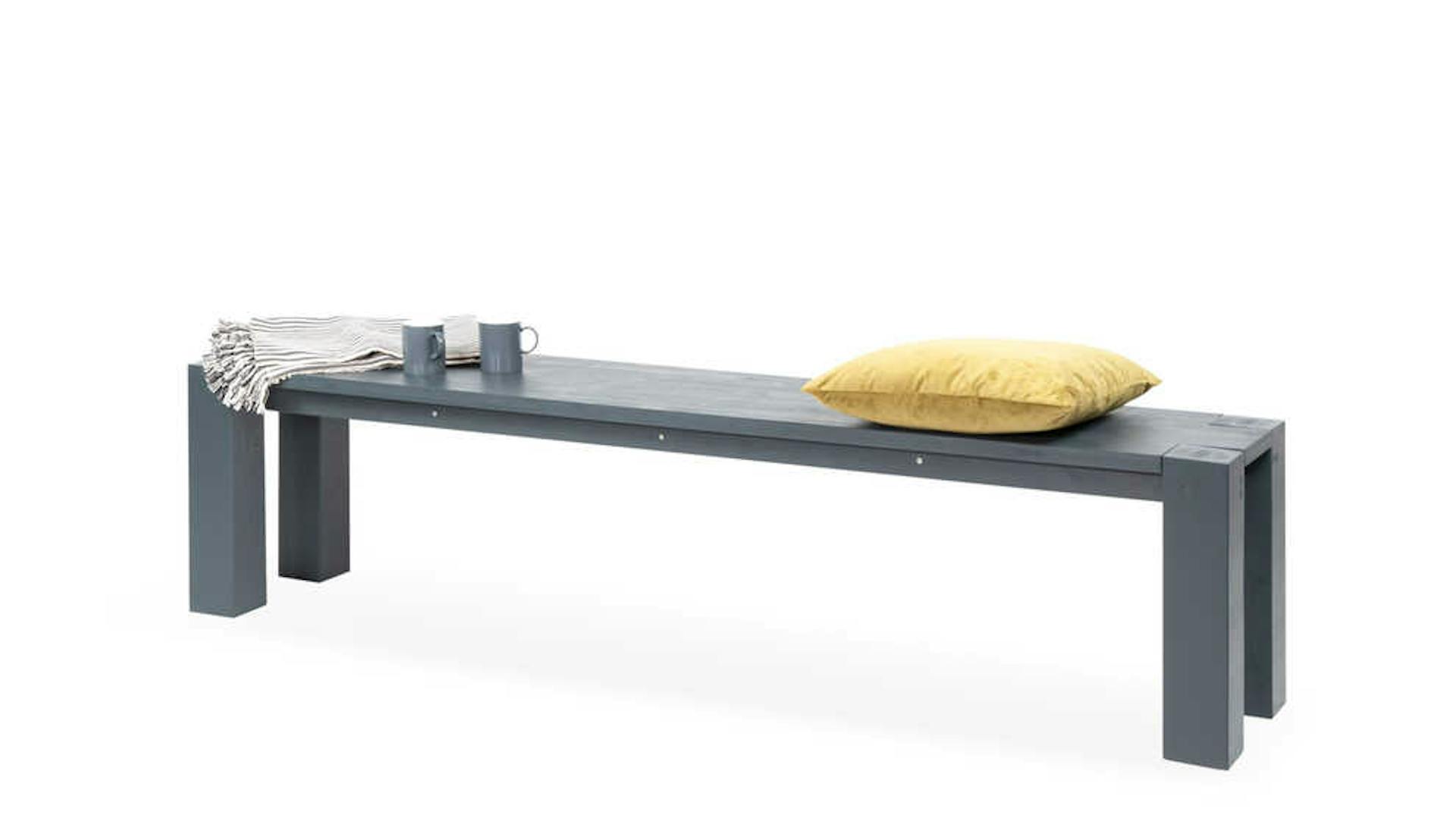 Bank Maren in grau mit gelbem Kissen.