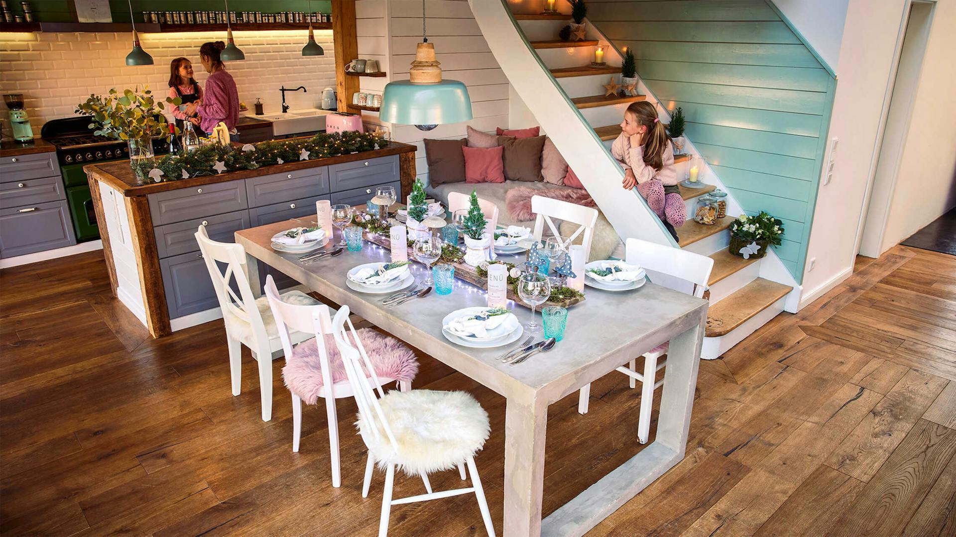 Betontisch Kalle, der mithilfe von Leuchtketten und weiterer Dekoration festlich gedeckt ist, steht inmitten des Esszimmers.