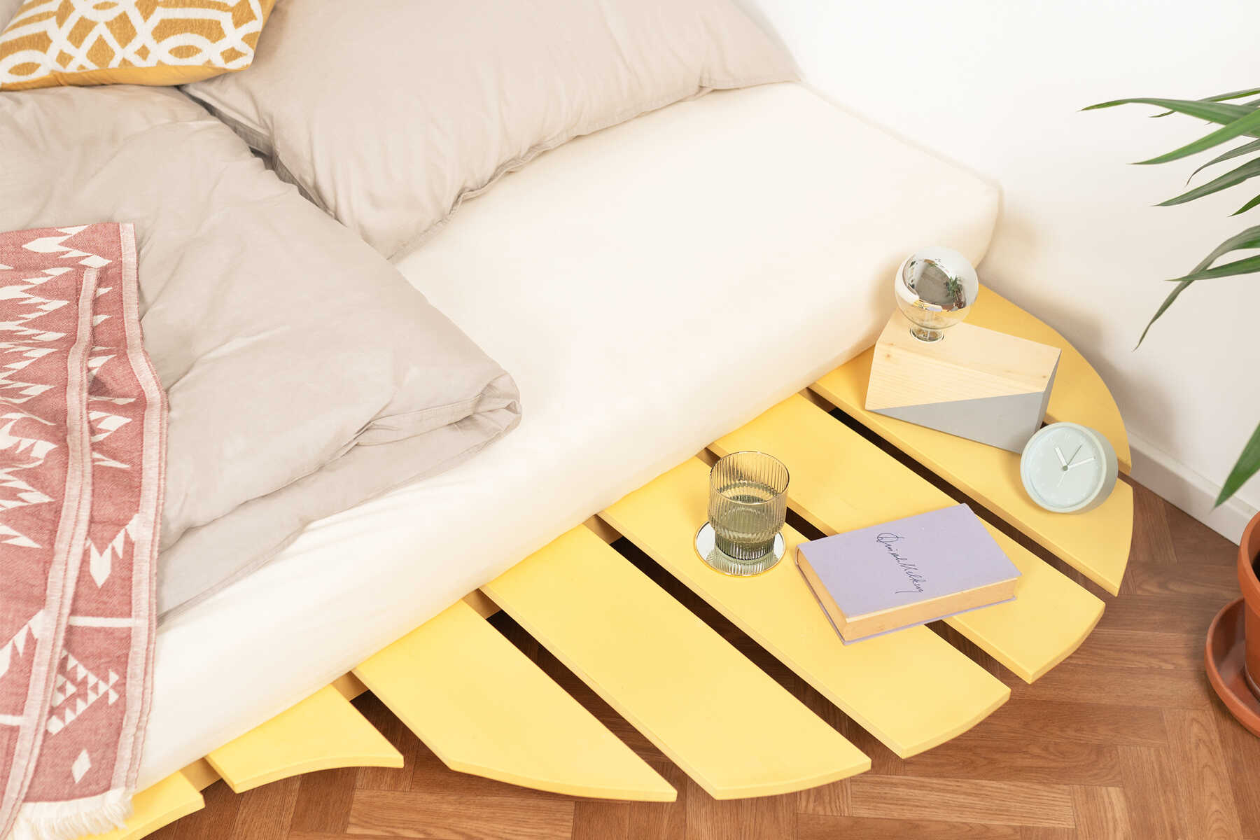 Detailansicht des aus Vollholz bestehenden Bett Ferdinand in gelb mit geschwungener Ablagefläche.