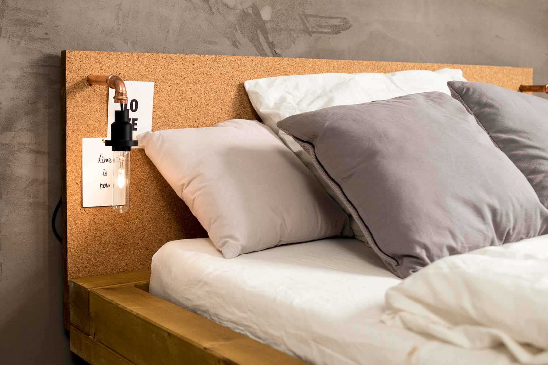 Seitliche Detailansicht des aus Vollholz bestehenden Bett Ludwig in Eichenfarbe mit Kopfteil aus Kork.