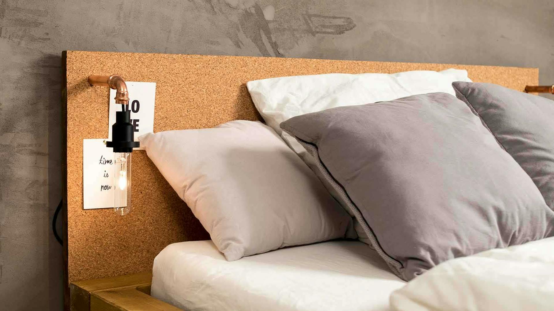 Seitliche Detailansicht des aus Vollholz bestehenden Bett Ludwig in Eichenfarbe mit Kopfteil aus Kork.