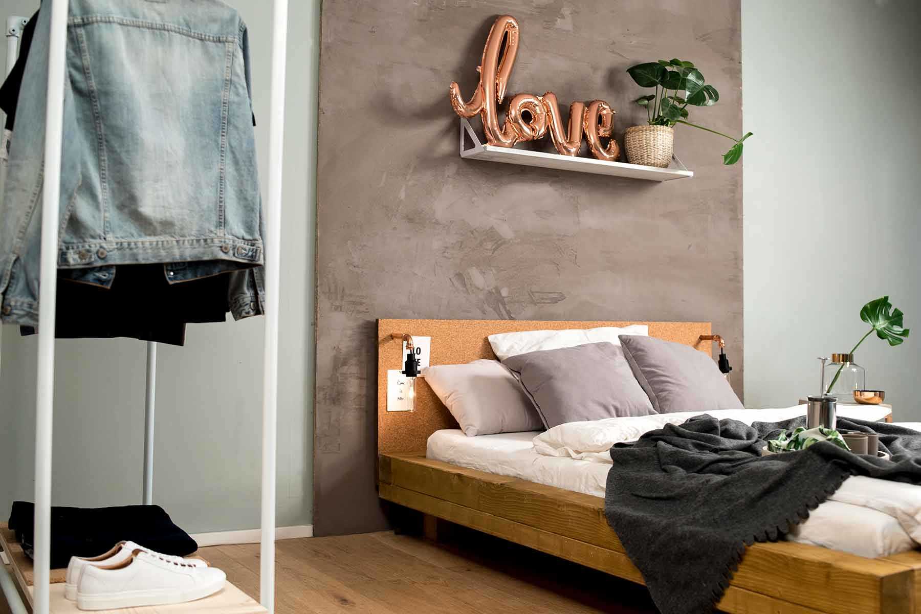 Seitliche Ansicht des aus Vollholz bestehenden Bett Ludwig in Eichenfarbe mit Kopfteil aus Kork.