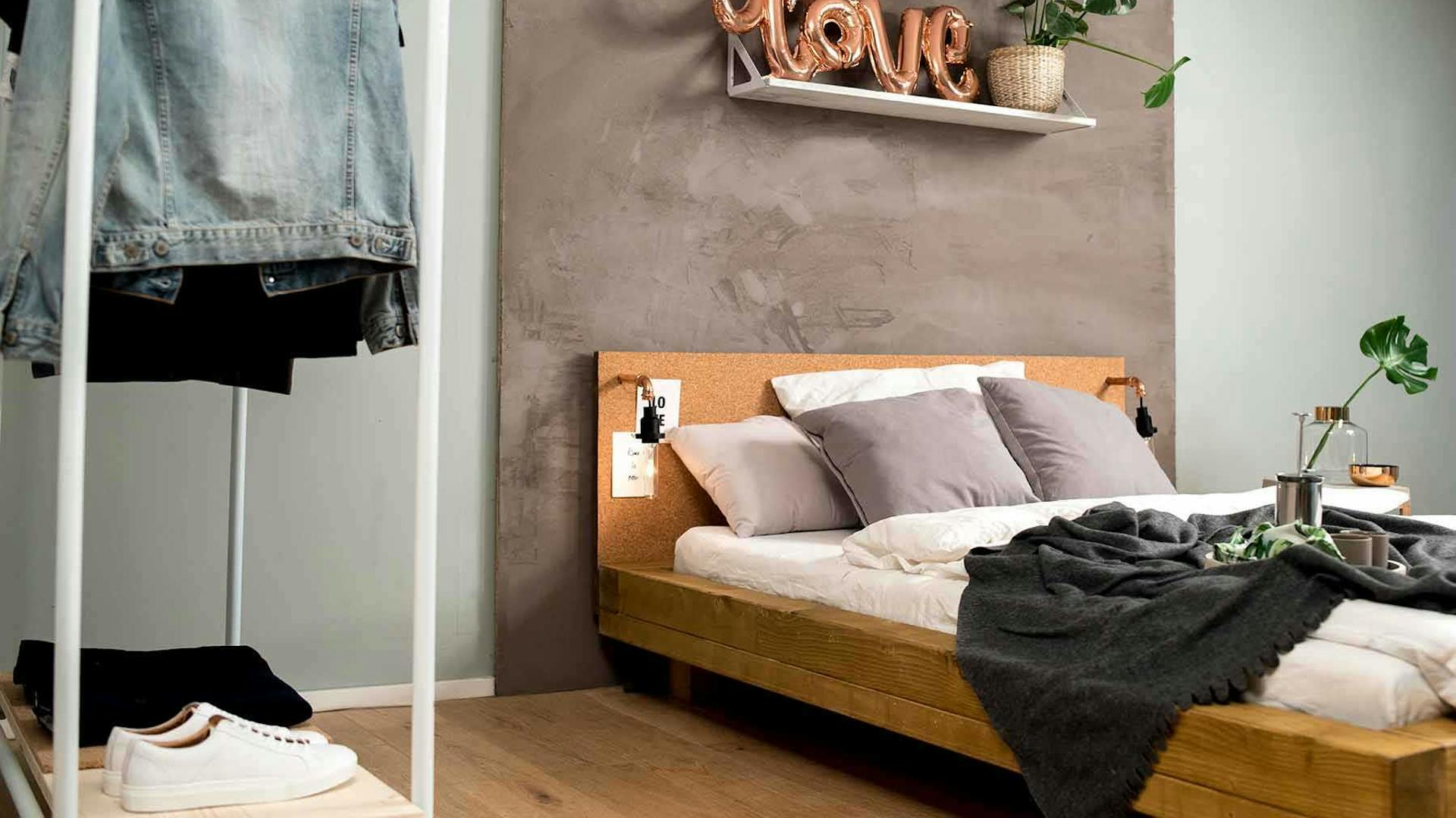 Seitliche Ansicht des aus Vollholz bestehenden Bett Ludwig in Eichenfarbe mit Kopfteil aus Kork.