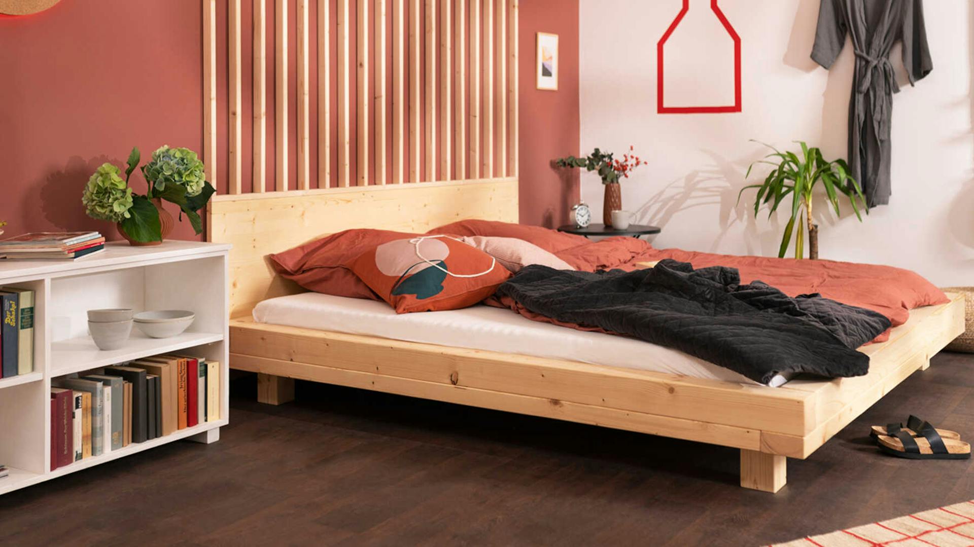 : Seitliche Ansicht des aus Vollholz bestehenden Bett Ludwig in Naturfarbe mit Kopfteil.