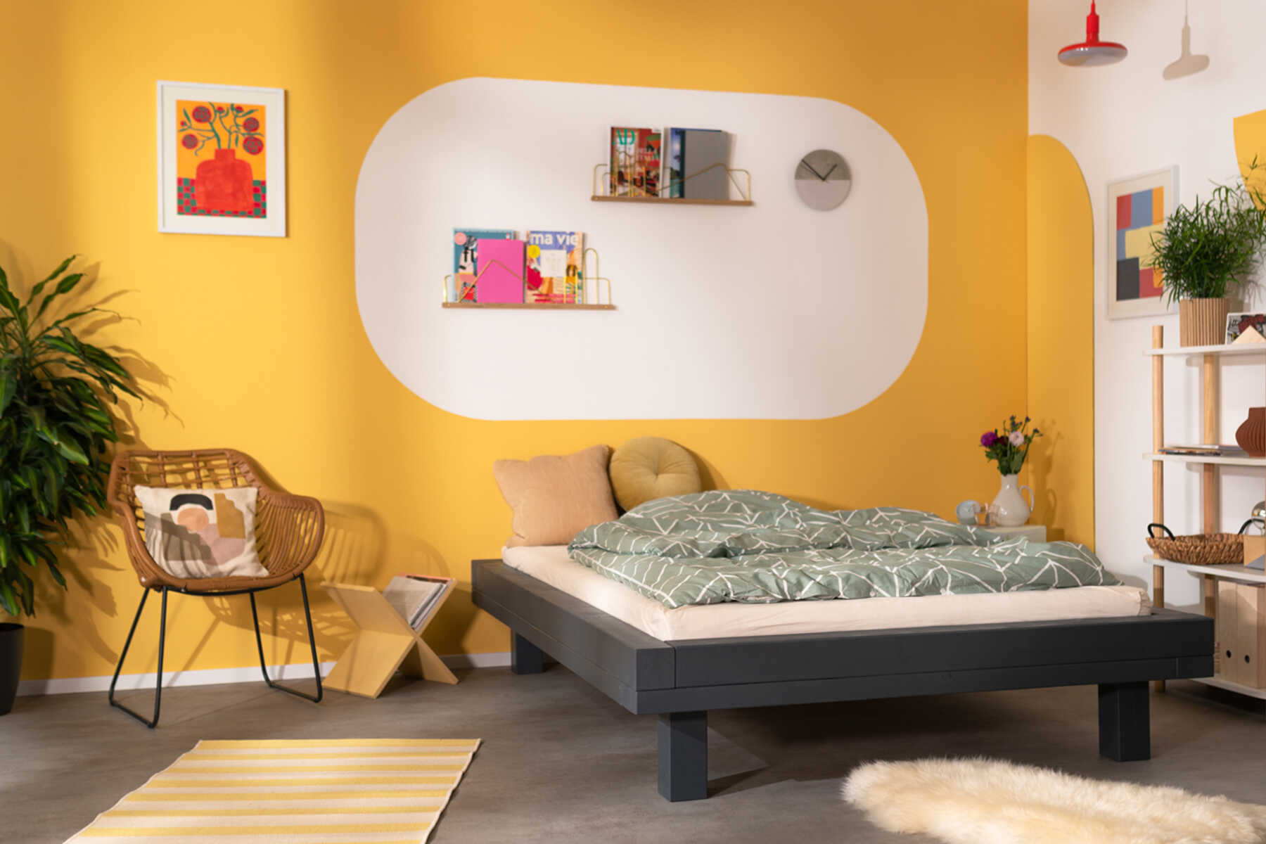 Frontansicht des aus Vollholz bestehenden Bett Ludwig in dunkel grau mit Kopfteil vor einer gelben Wand.
