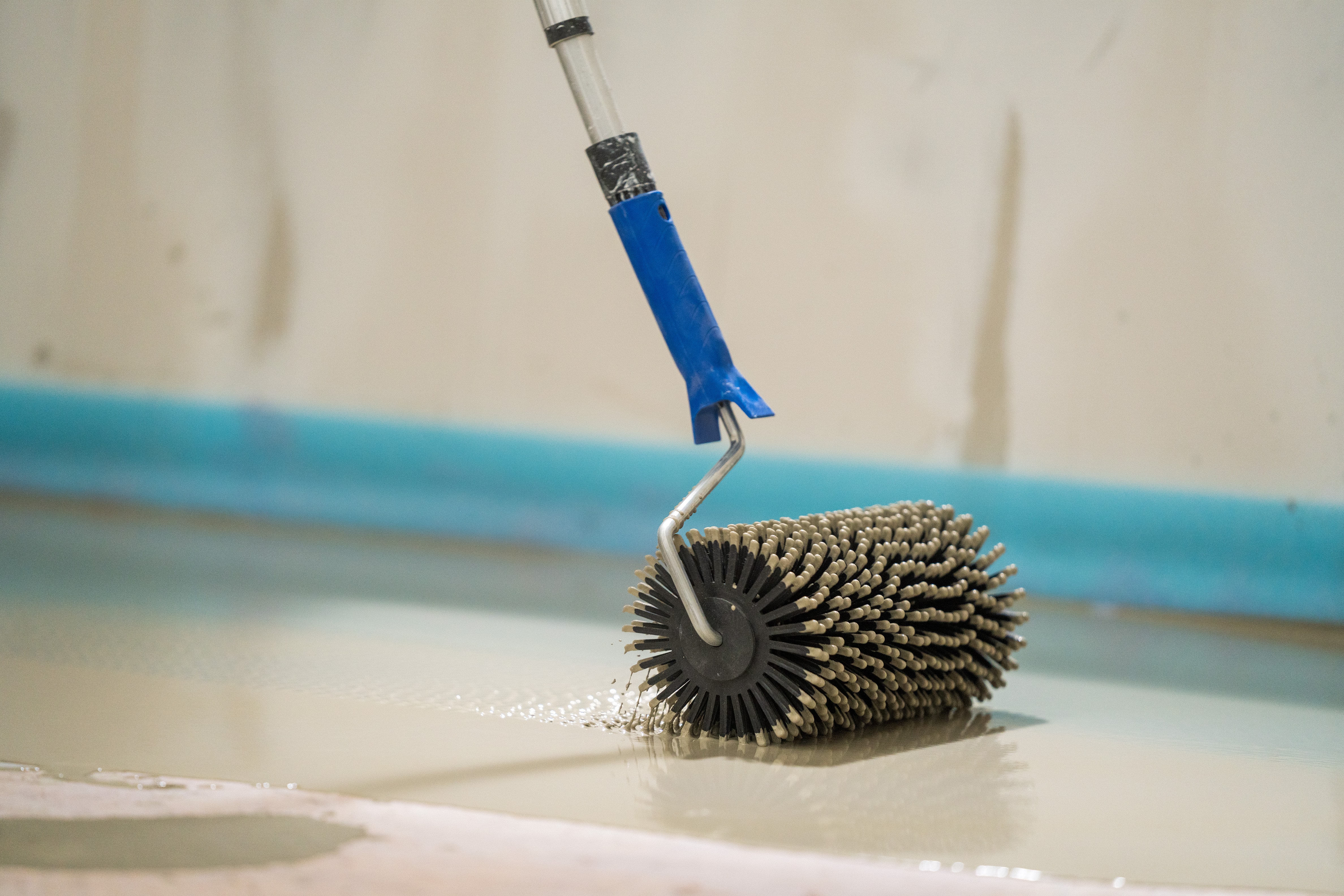 Heimwerker rollt mit Stachelwalze über Ausgleichsmasse.