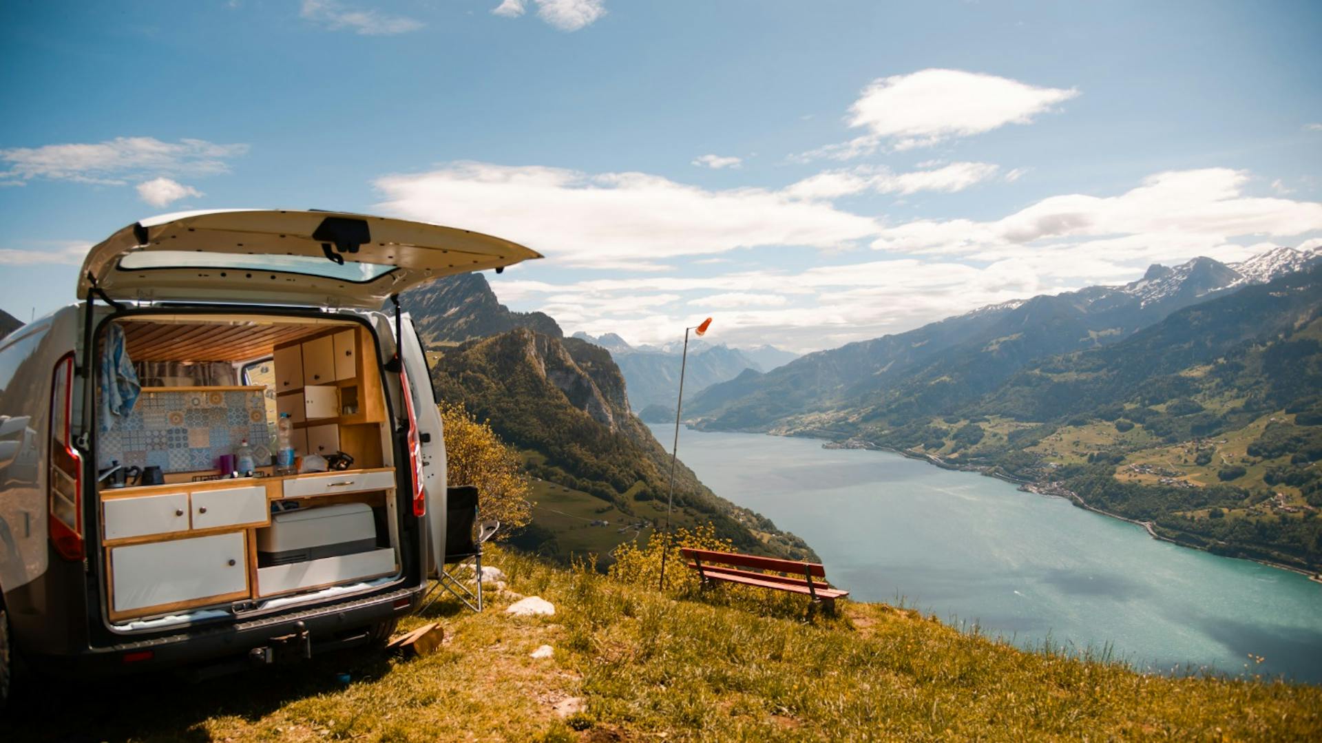Ein selbst umgebauter Camper steht an einem Bergsee mit Panorama-Blick