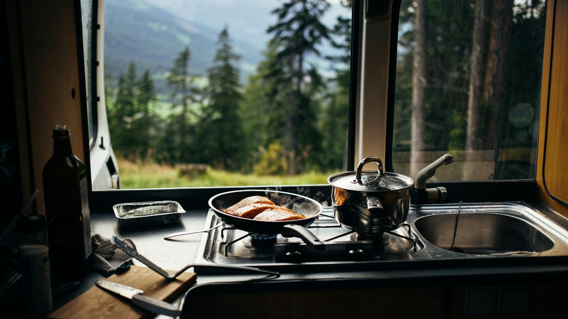 Kochstelle in Camper-Van vor einem Fenster mit Blick auf eine Waldfläche