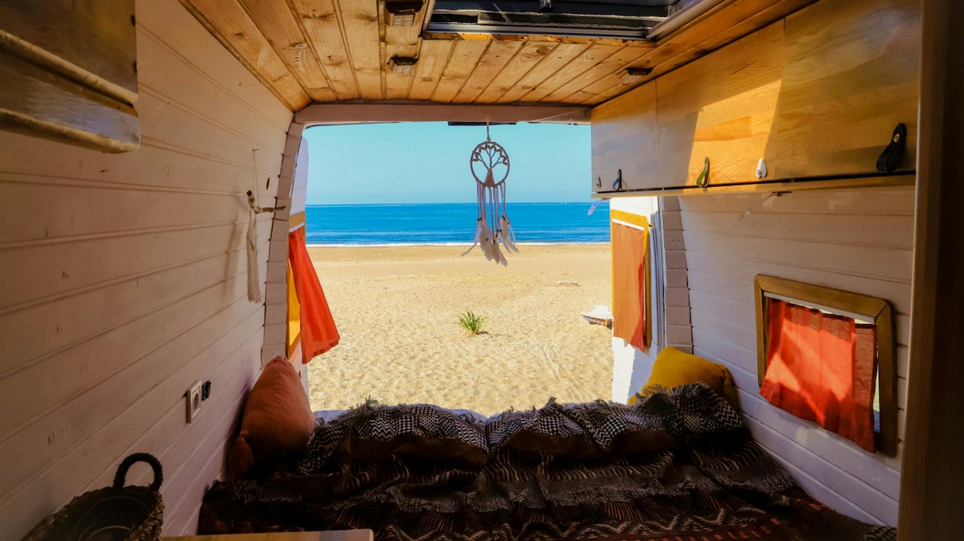Camper mit hölzerner Wandverkleidung und Blick auf Sandstrand
