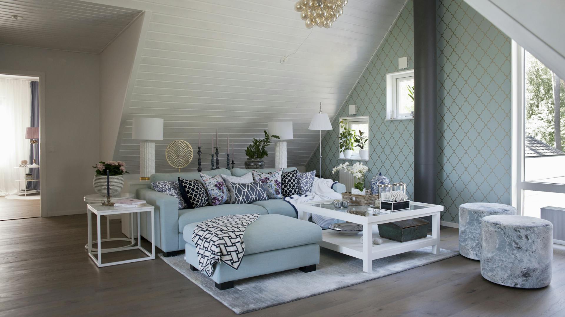 Gemütlich eingerichtetes Wohnzimmer unter Dachschräge mit Couch, Teppich, Tisch und Dekoration