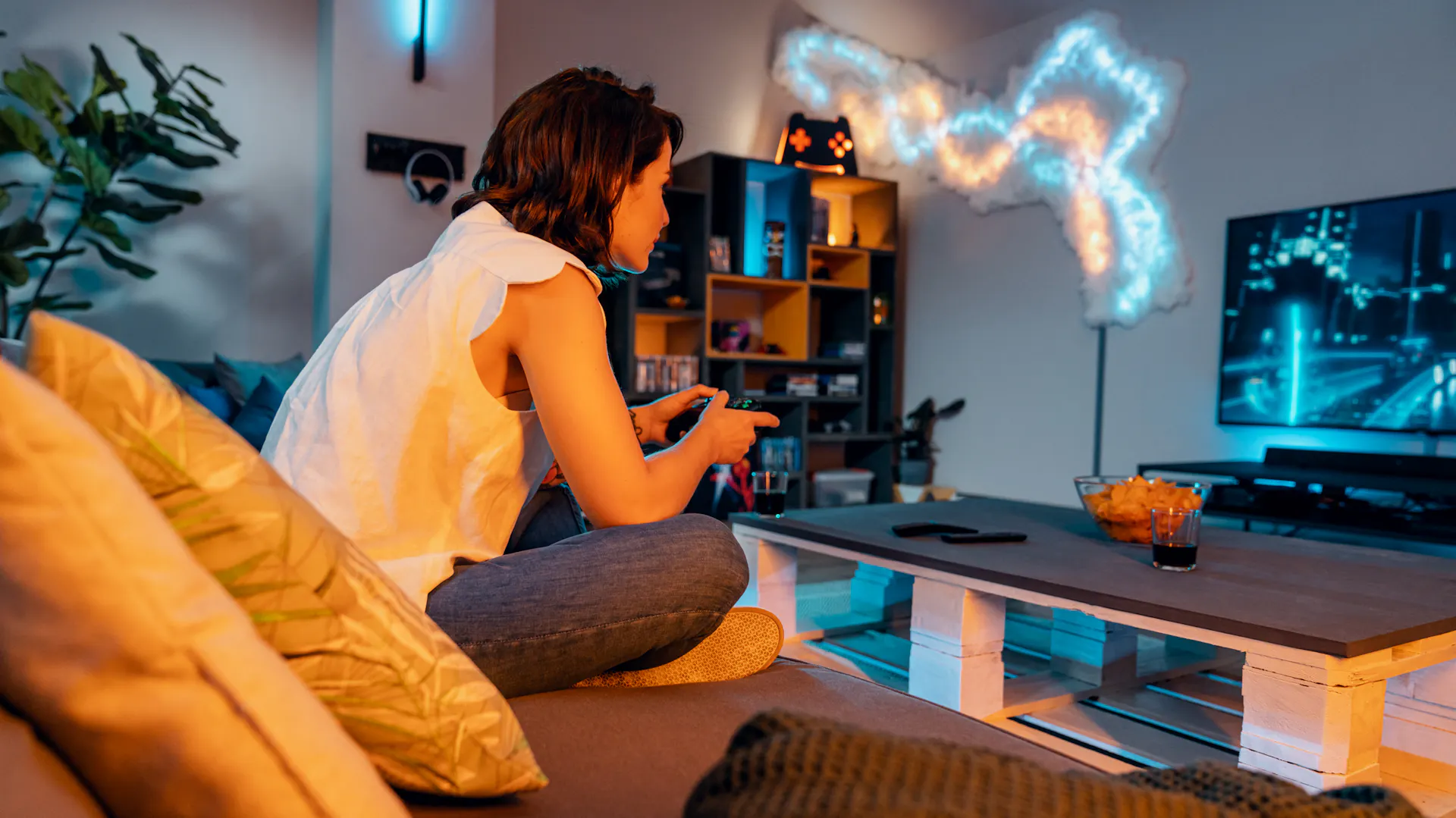 Frau im Gaming-Zimmer mit Controller in der Hand auf der Couch