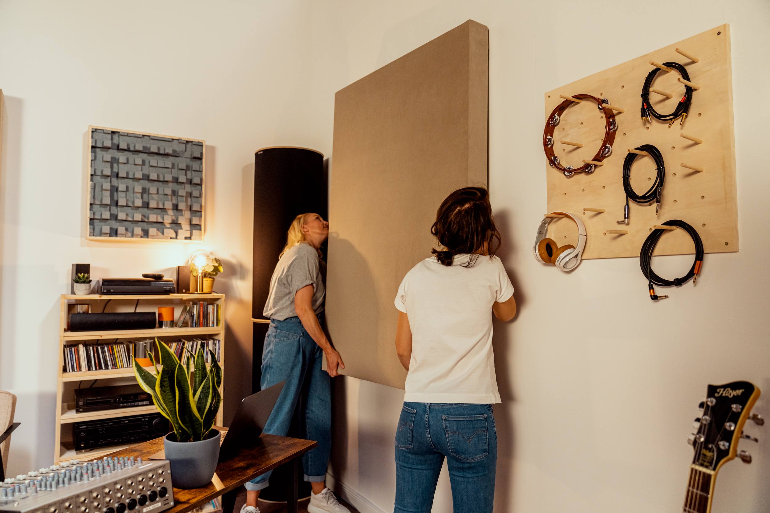 Zwei Frauen hängen einen Schallabsorber im Musikzimmer auf