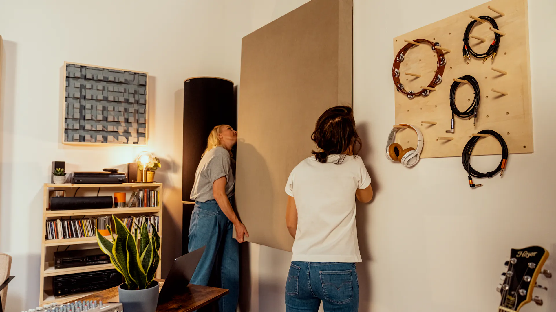 Zwei Frauen hängen einen Schallabsorber im Musikzimmer auf