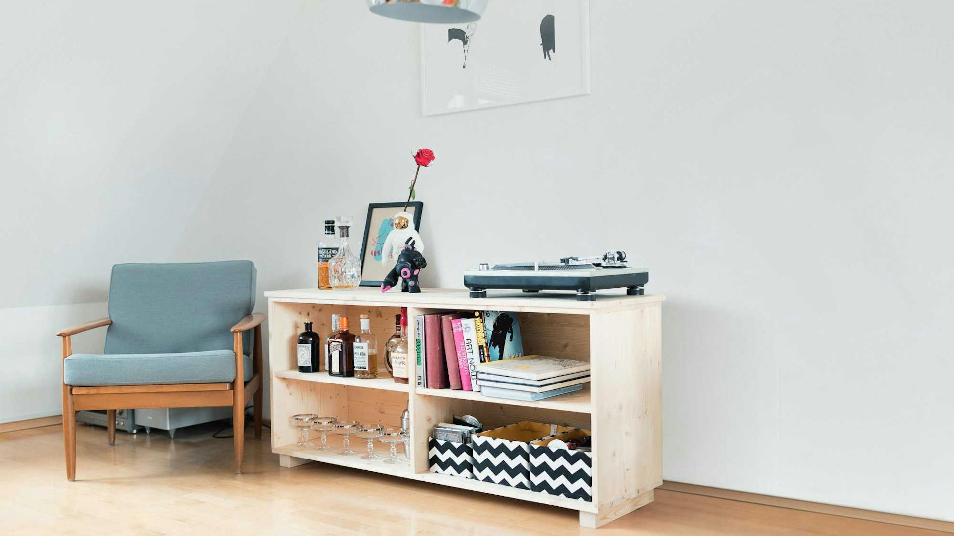 Scaffale in legno basso accanto a una poltrona in una stanza con tetto inclinato