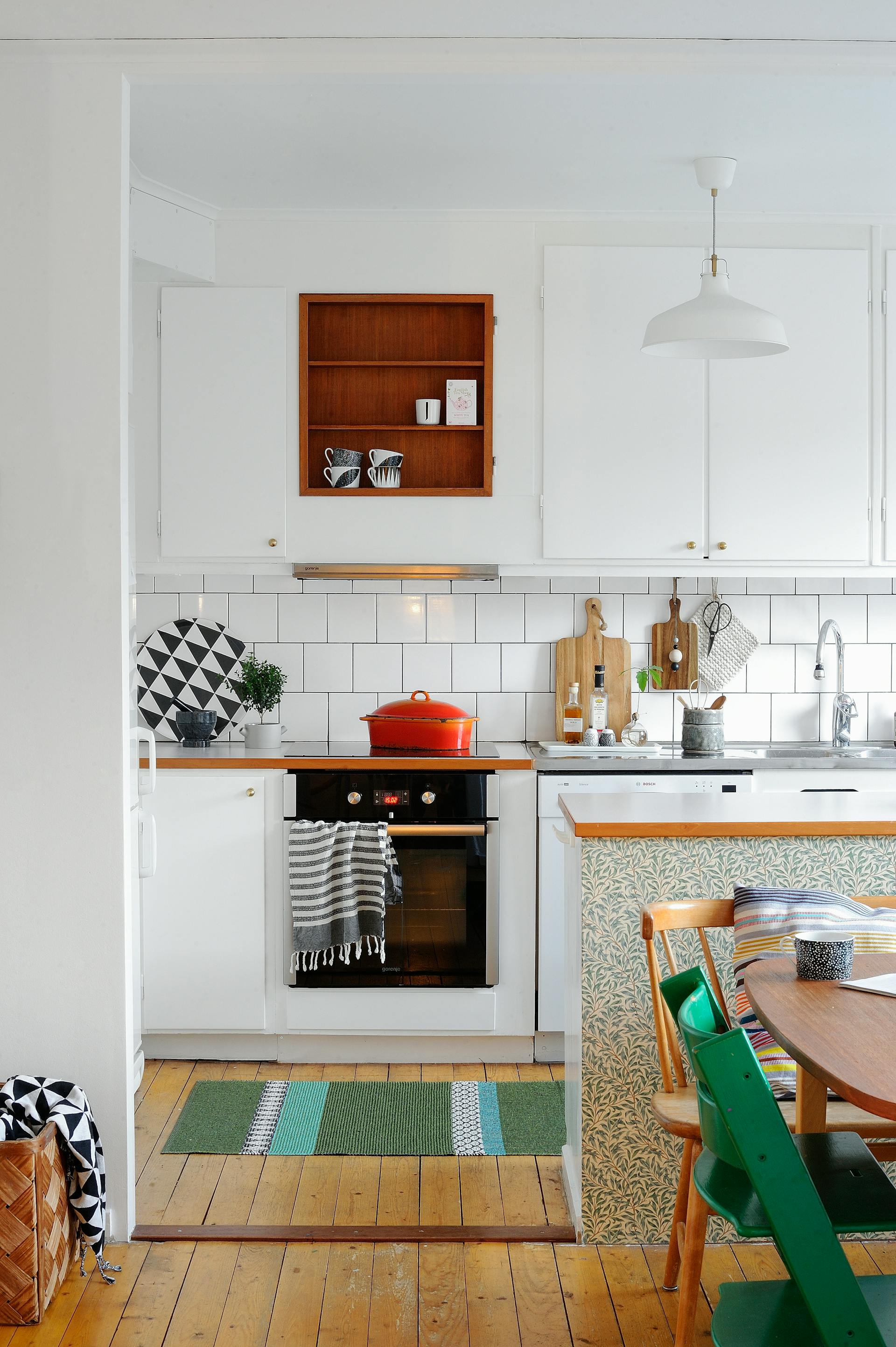 Soggiorno e sala da pranzo bianchi con pavimento a listoni.