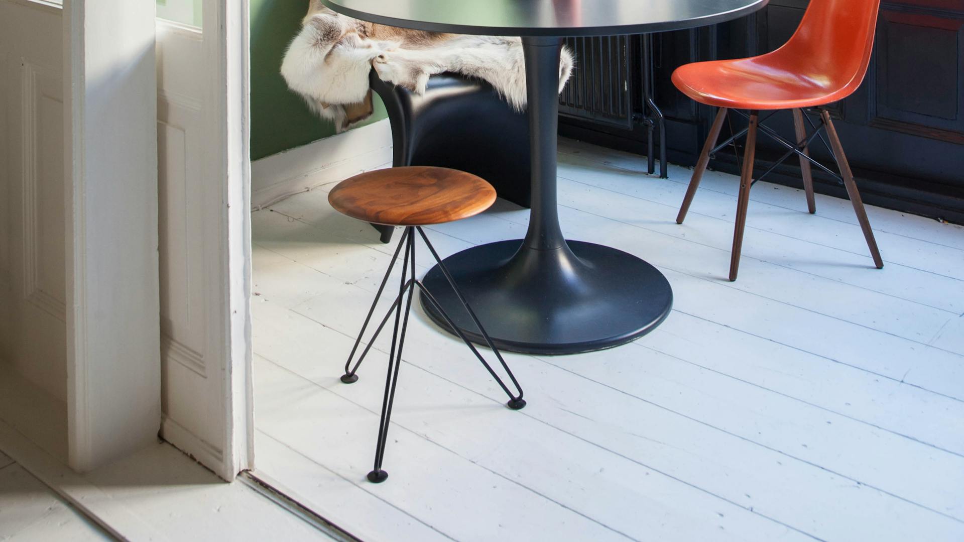 Ein heller Dielenboden in einem Grün gestrichenen Wintergarten mit Essecke