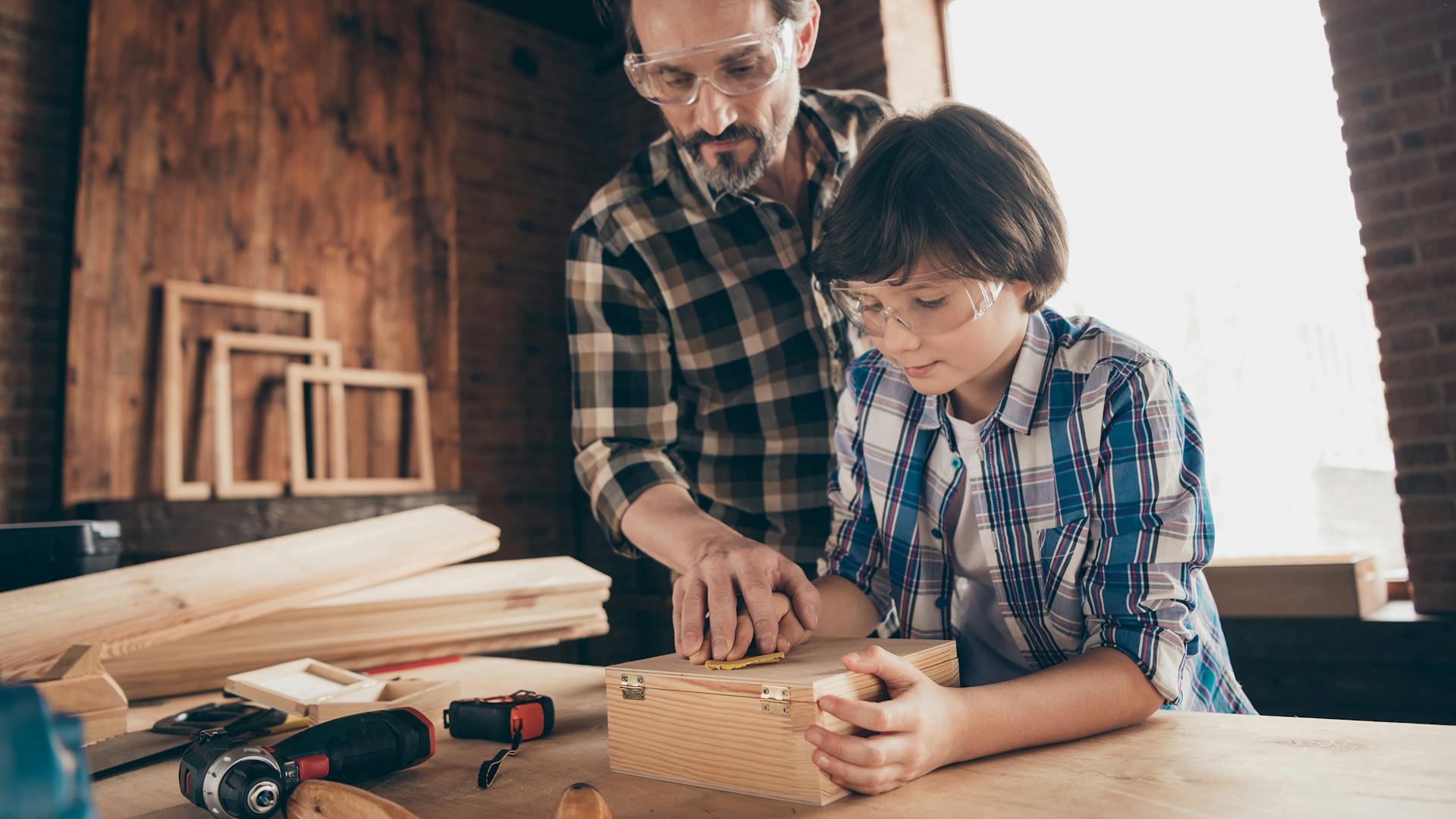 Vater macht Holzarbeiten in einer Werkstatt mit seinem Kind