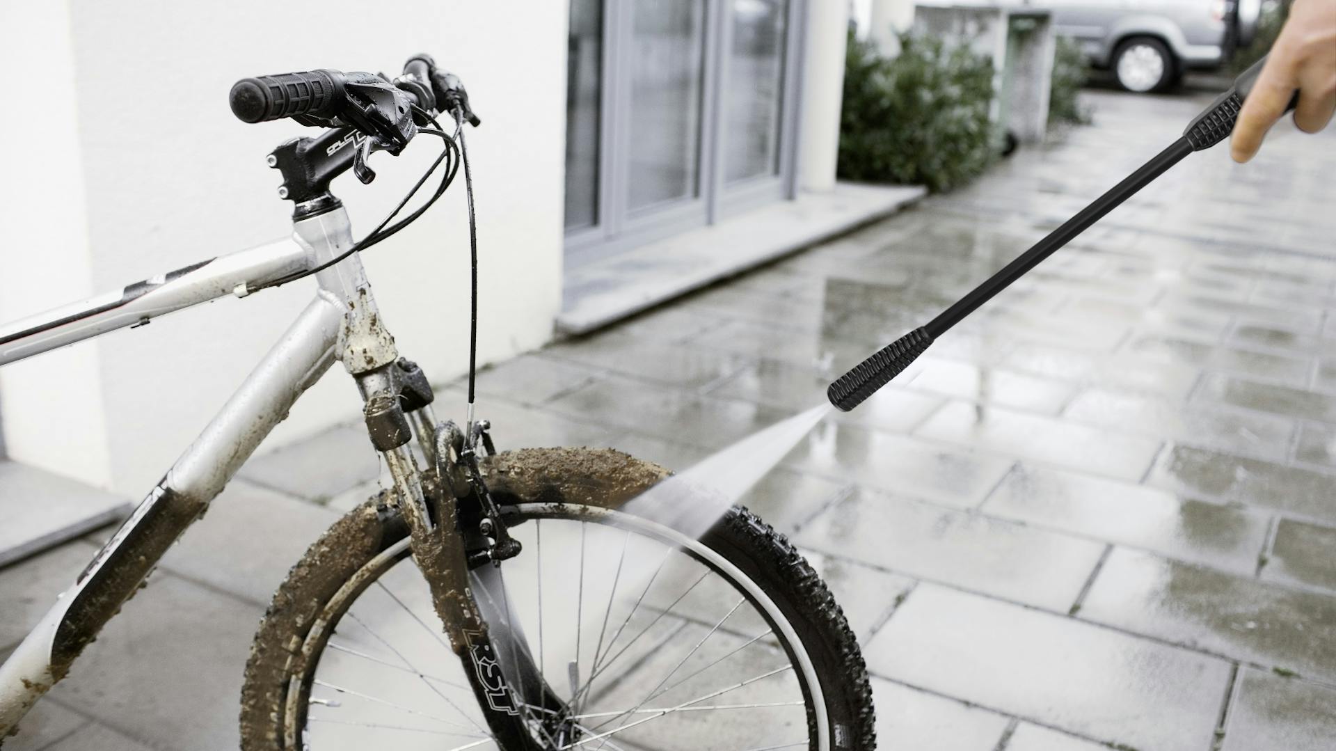 Grober Schmutz wird vom Vorderreifen eines Fahrrads mit dem Hochdruckreiniger abgesprengt