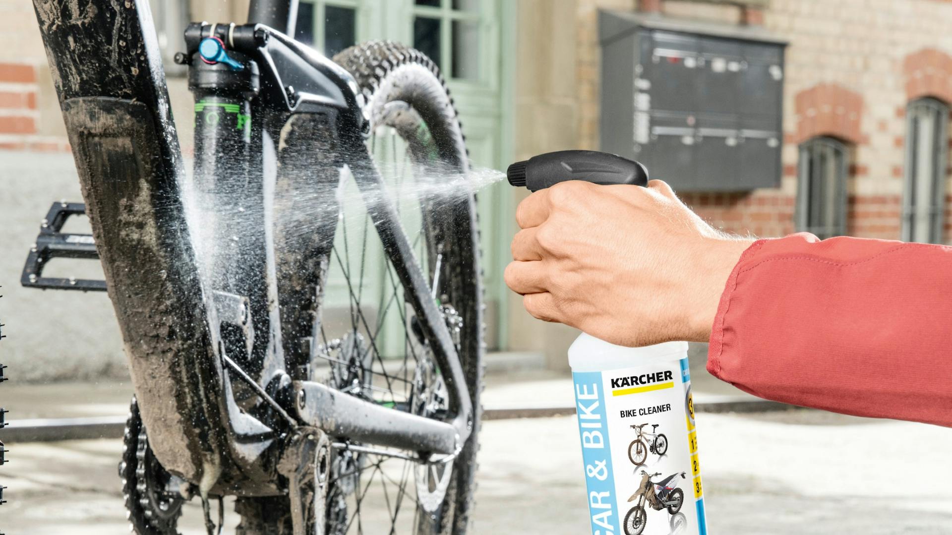 Fahrradreiniger wird auf Rahmen von hartnäckig verschmutztem Fahrrad aufgebracht