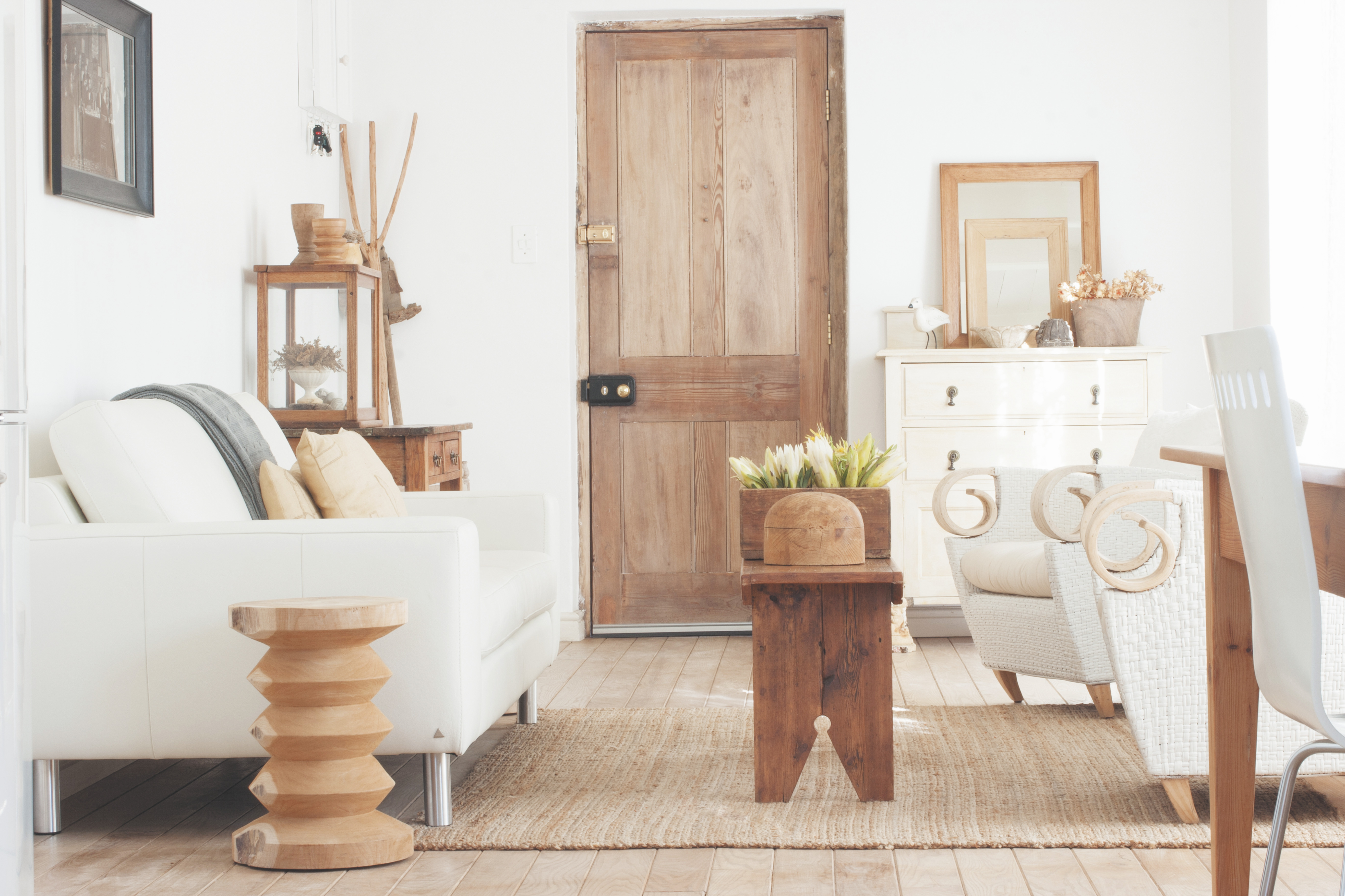 Ein Sofa und ein Sessel stehen im Wohnzimmer. Im Hintergrund sieht man eine Holztür.