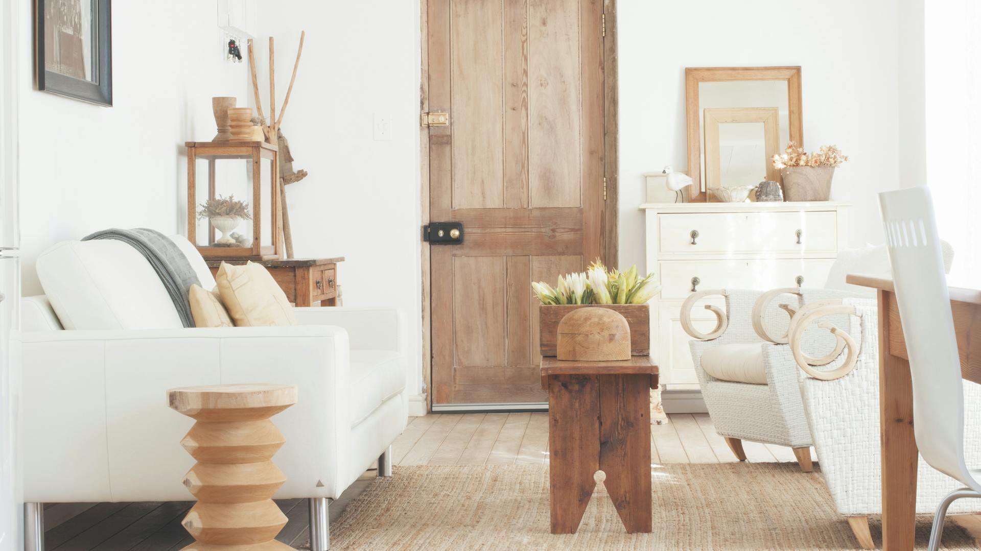 Ein Sofa und ein Sessel stehen im Wohnzimmer. Im Hintergrund sieht man eine Holztür.