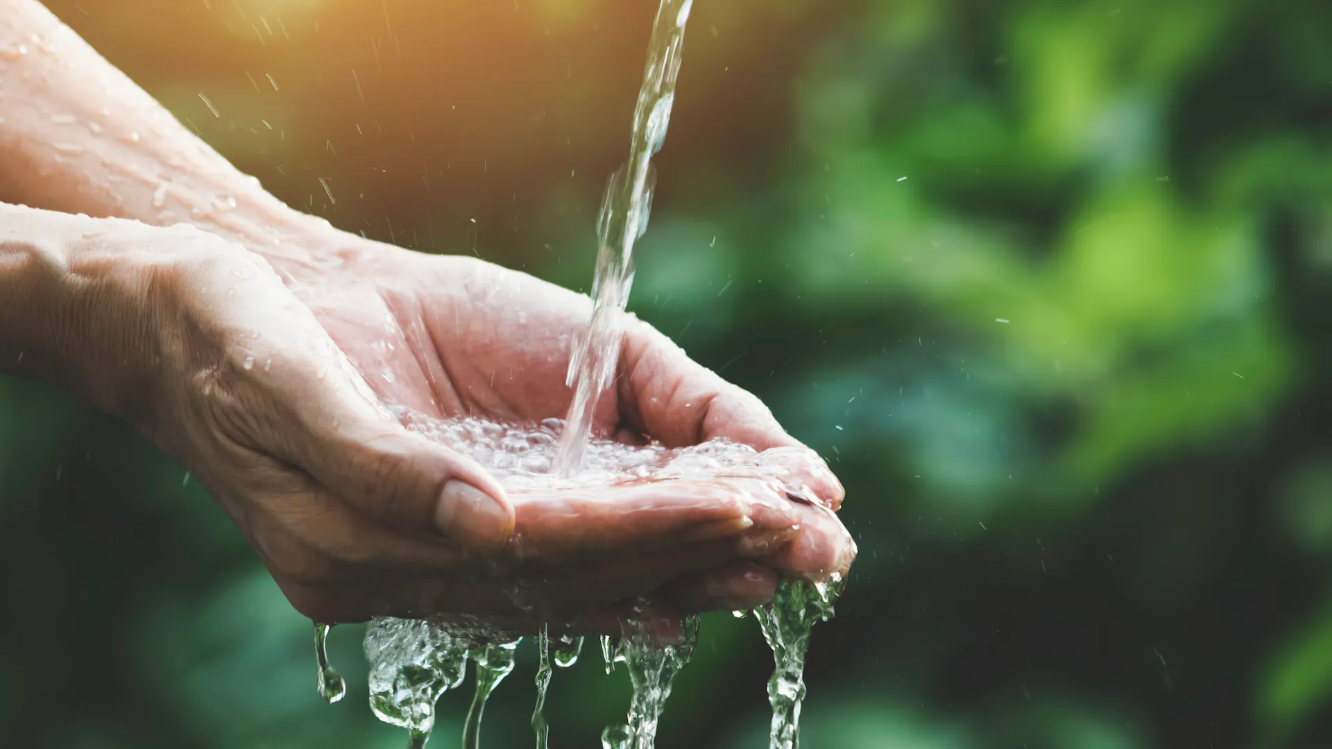 Wasser tropft auf Hände.