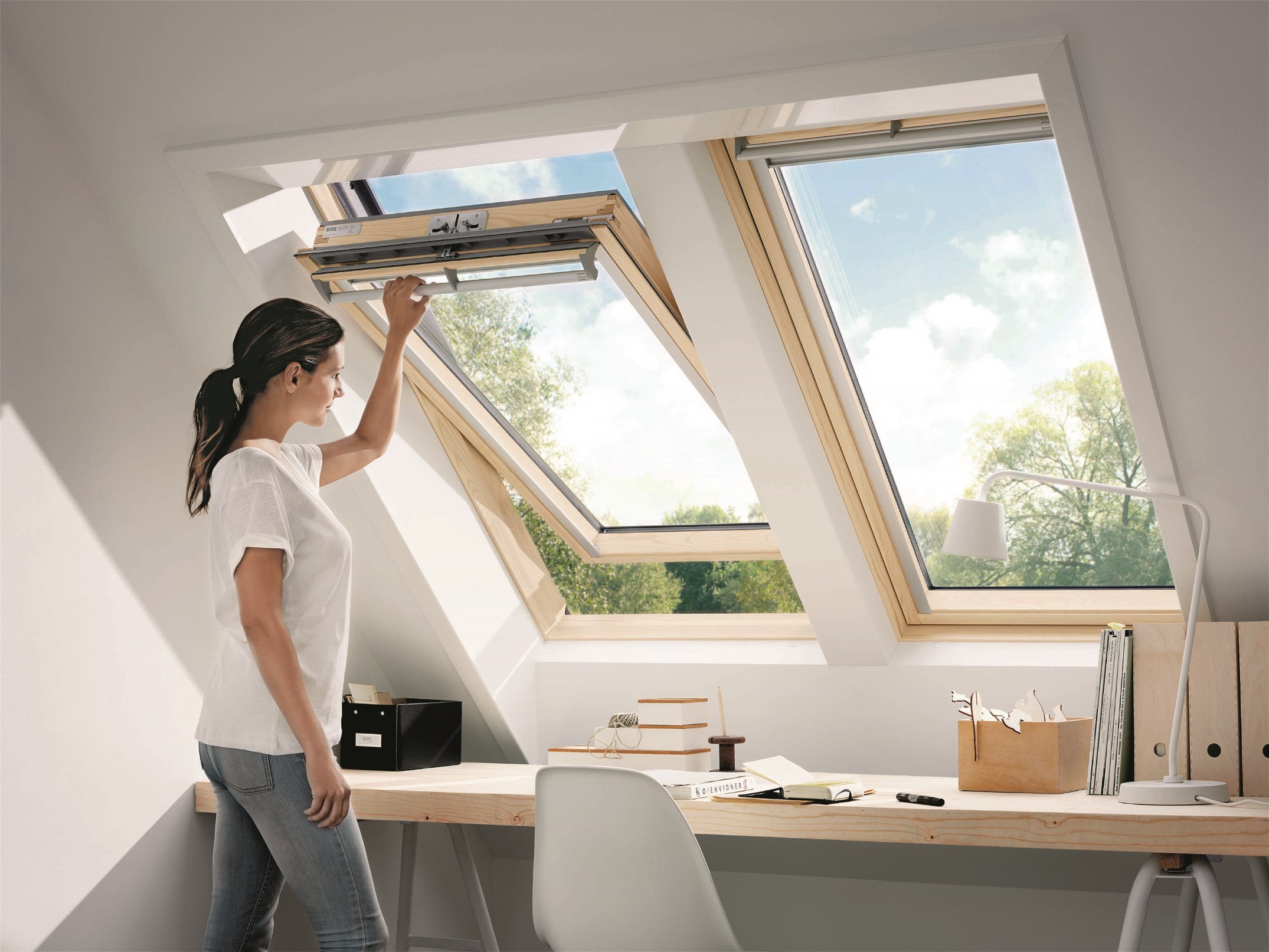 Egy nő tiszta ablakot nyit ki a tetőtérben.