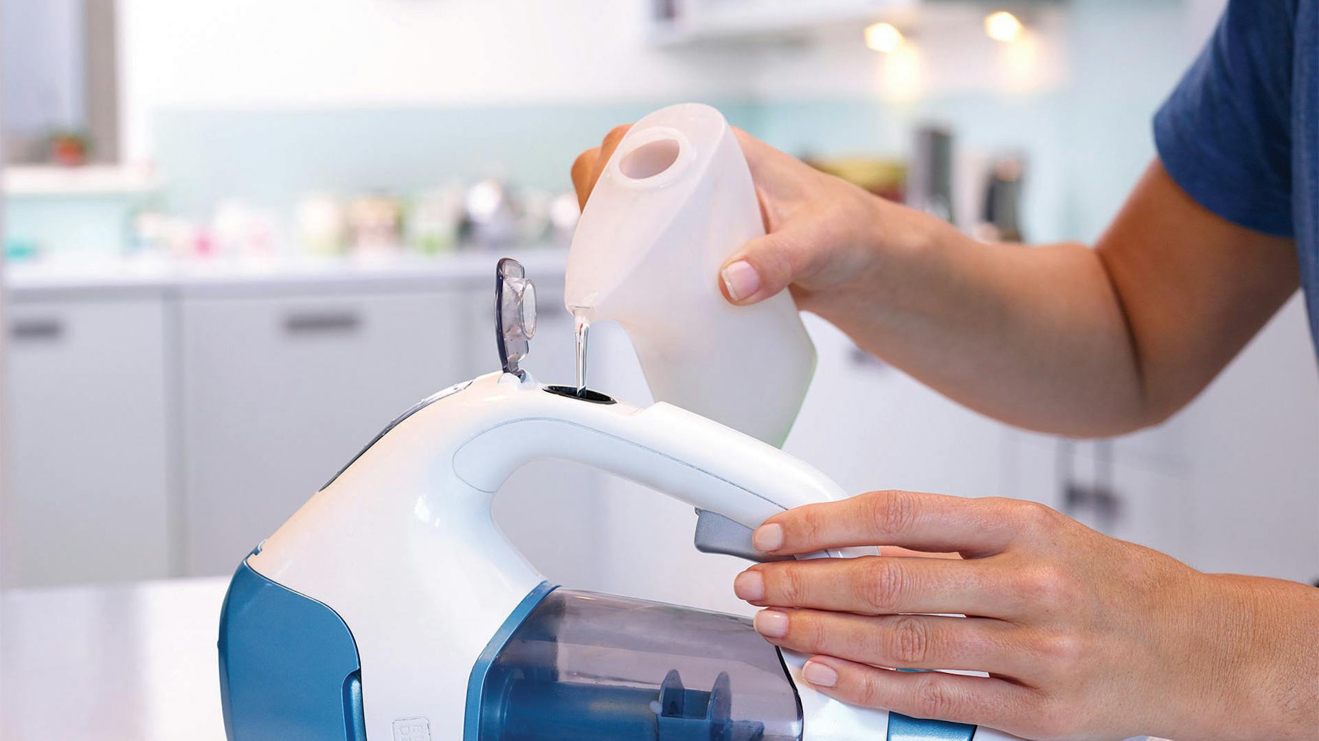 Jemand füllt Reinigungsmittel in den Akkuwischer vor der Fensterreinigung.