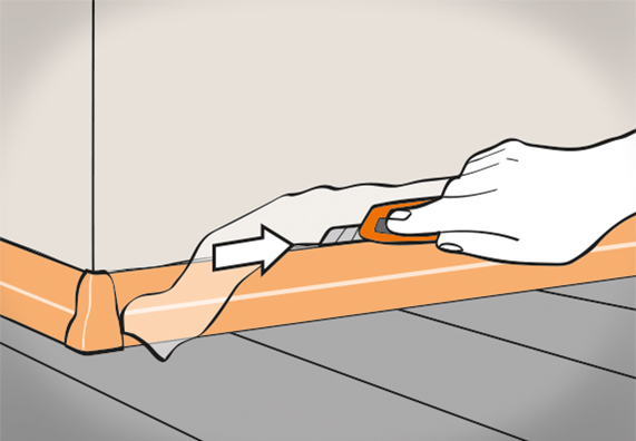 Jemand schneidet die überschüssige Unterlegfolie einer Sockelleiste ab