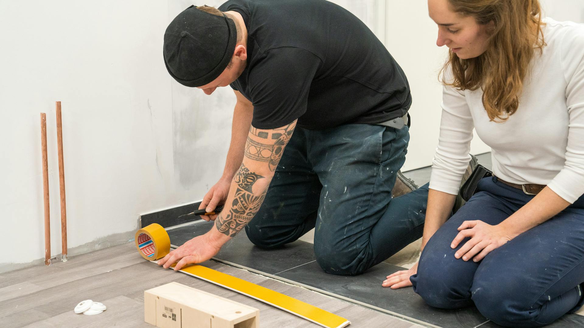 Handwerker befestigt eine Fußleiste mit doppelseitigem Klebeband.