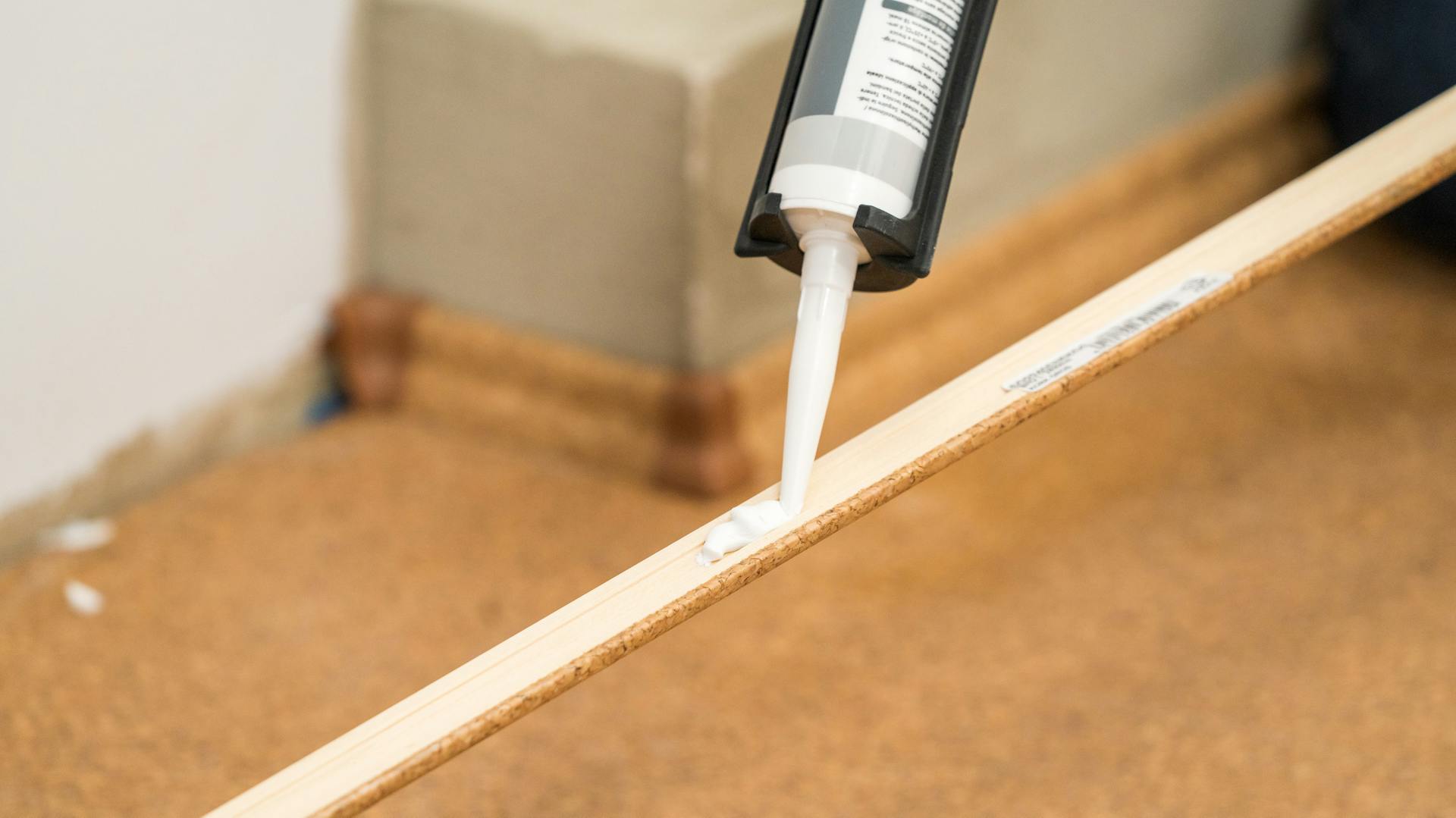 Handwerker befestigt eine Fußleiste mit Montagekleber.