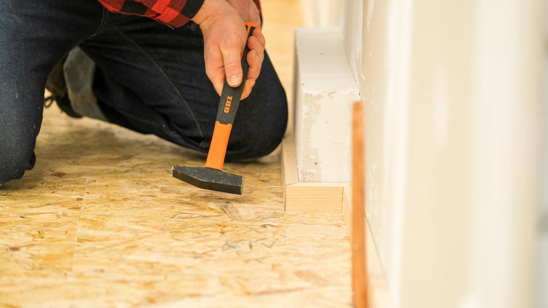 Handwerker befestigt eine Fußleiste mit Stahlnägeln.