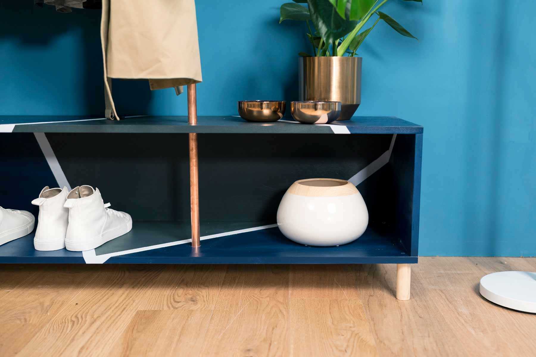 Detailansicht der aus Kupferrohren und Vollholz bestehenden Garderobe Merle in dunkel blau mit viel Stauraum.