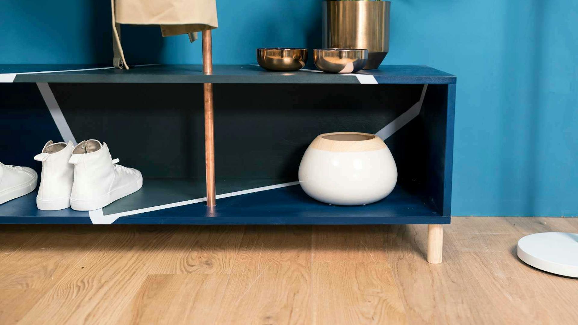 Detailansicht der aus Kupferrohren und Vollholz bestehenden Garderobe Merle in dunkel blau mit viel Stauraum.