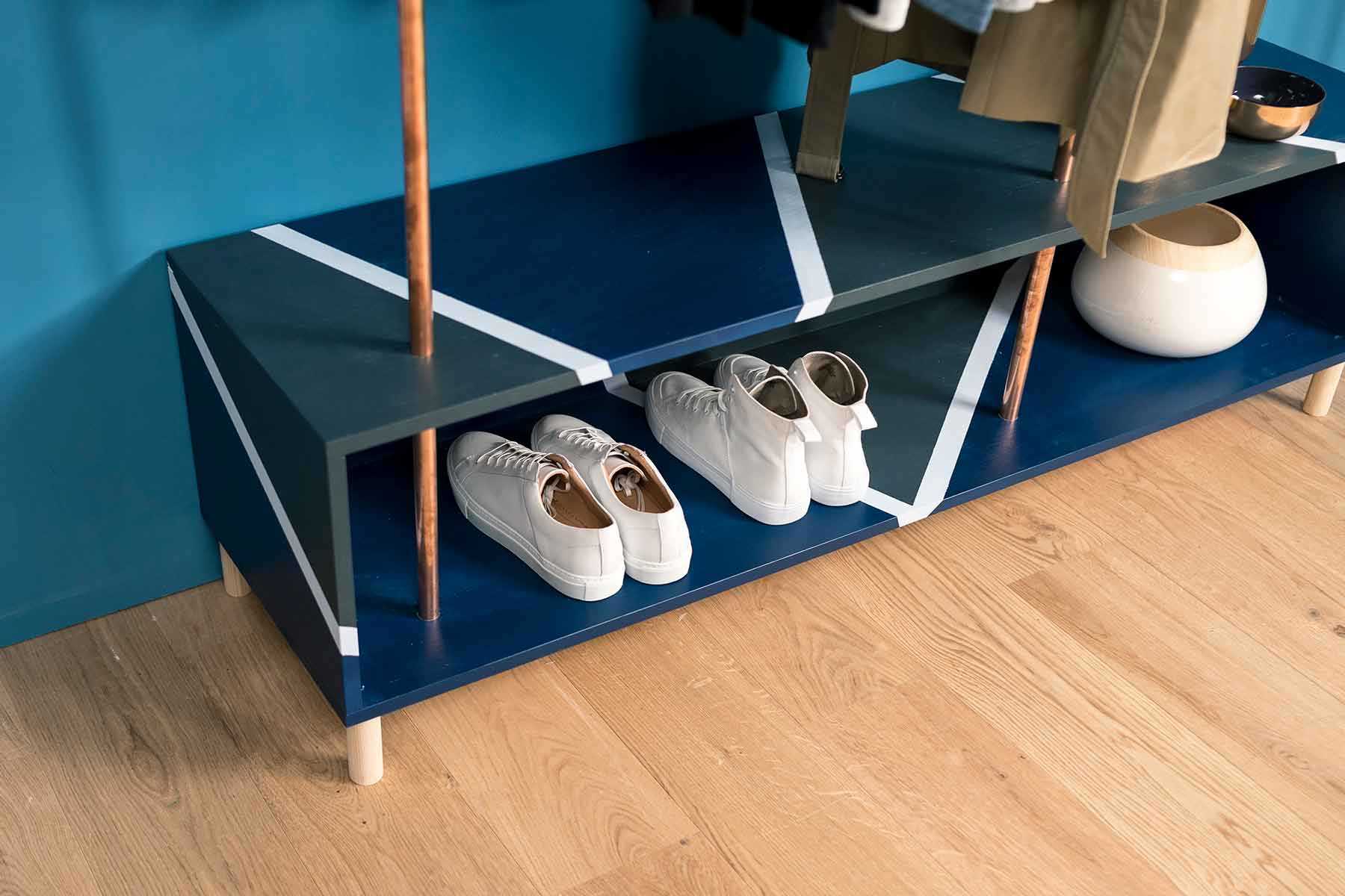 Seitliche Ansicht der aus Kupferrohren und Vollholz bestehenden Garderobe Merle in dunkel blau mit viel Stauraum.