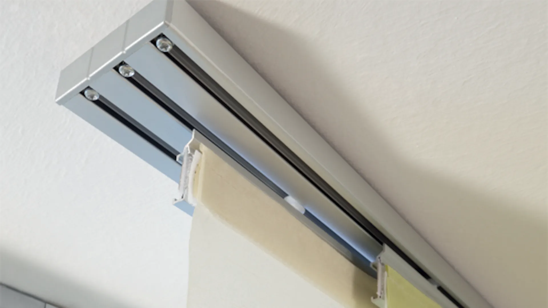 Dreiläufige Gardinenschiene an Decke.