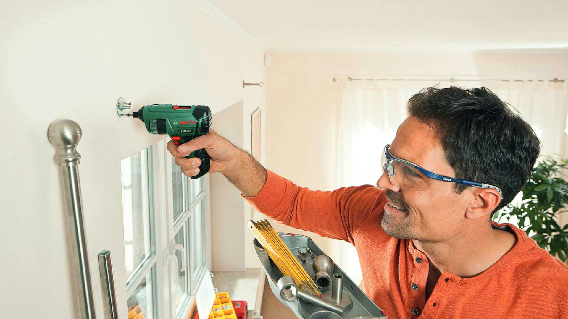 Mann mit Akkuschrauber an Wand